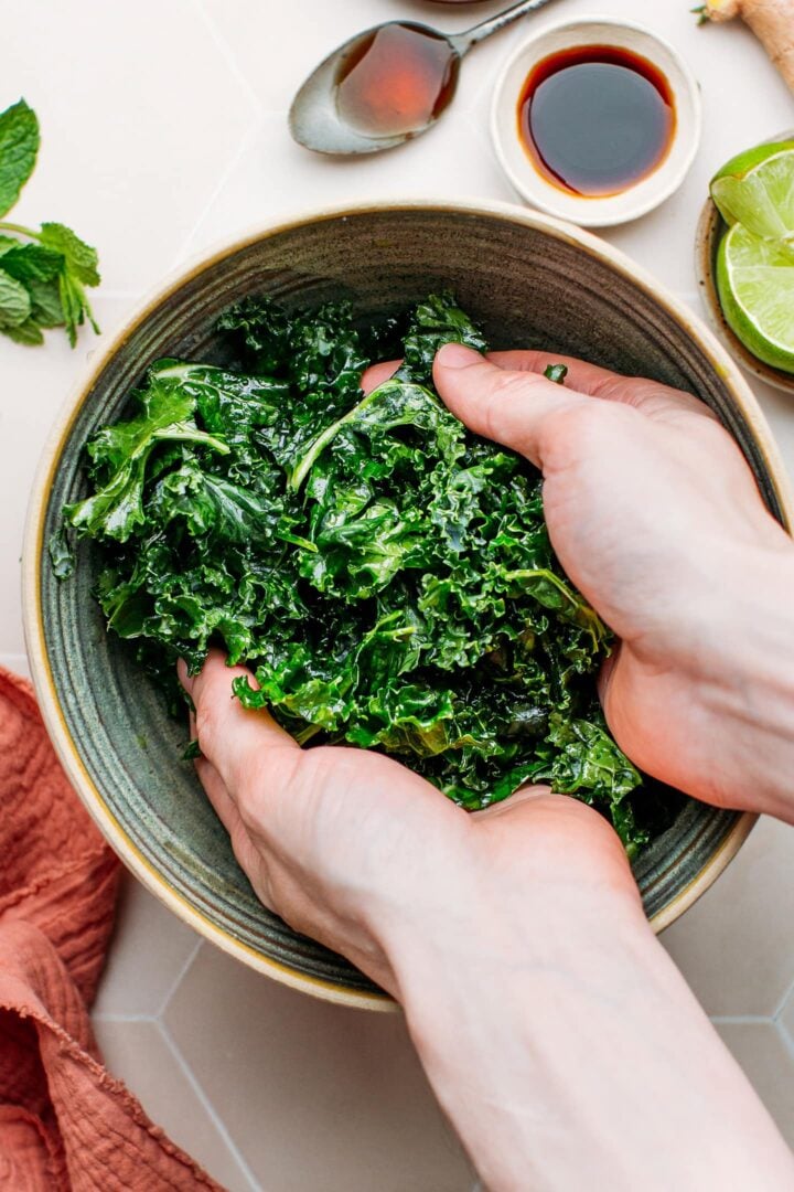 Massaging kale in a bowl.