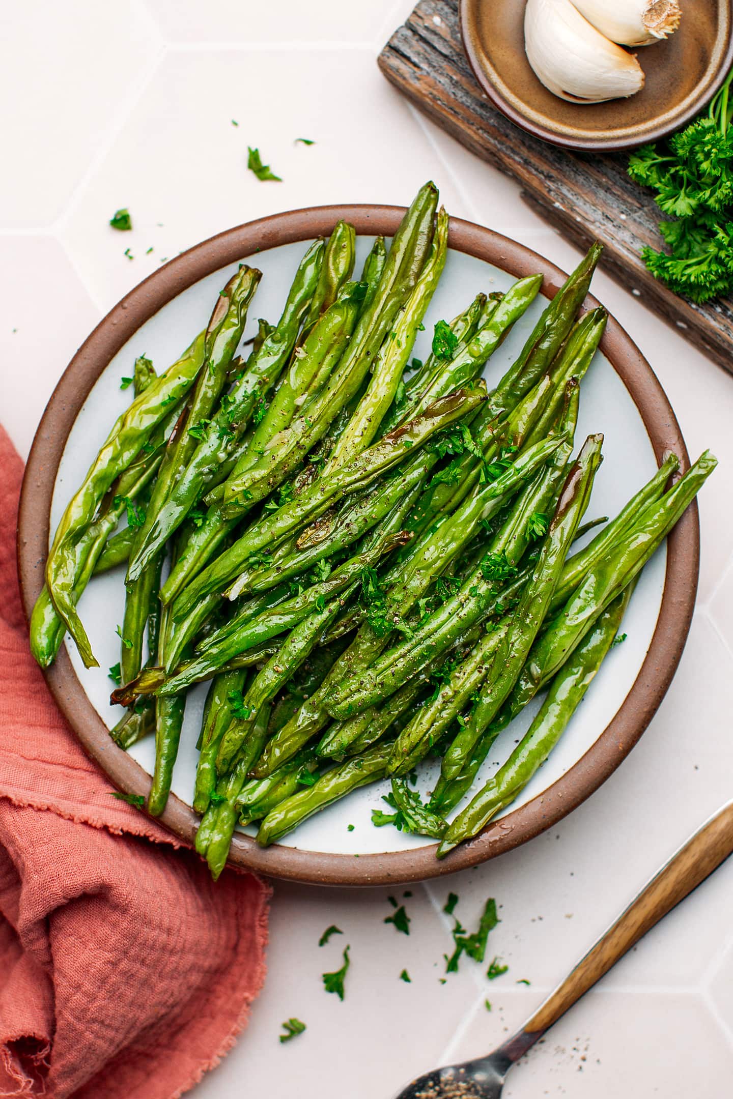 Cooked green beans topped with black pepper on a plate.