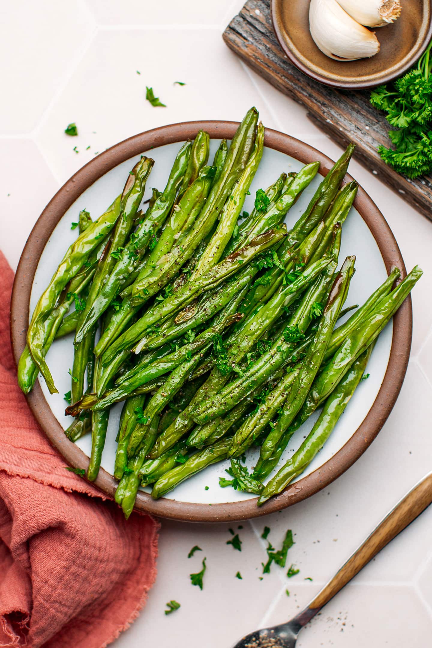 Cooked green beans topped with black pepper on a plate.