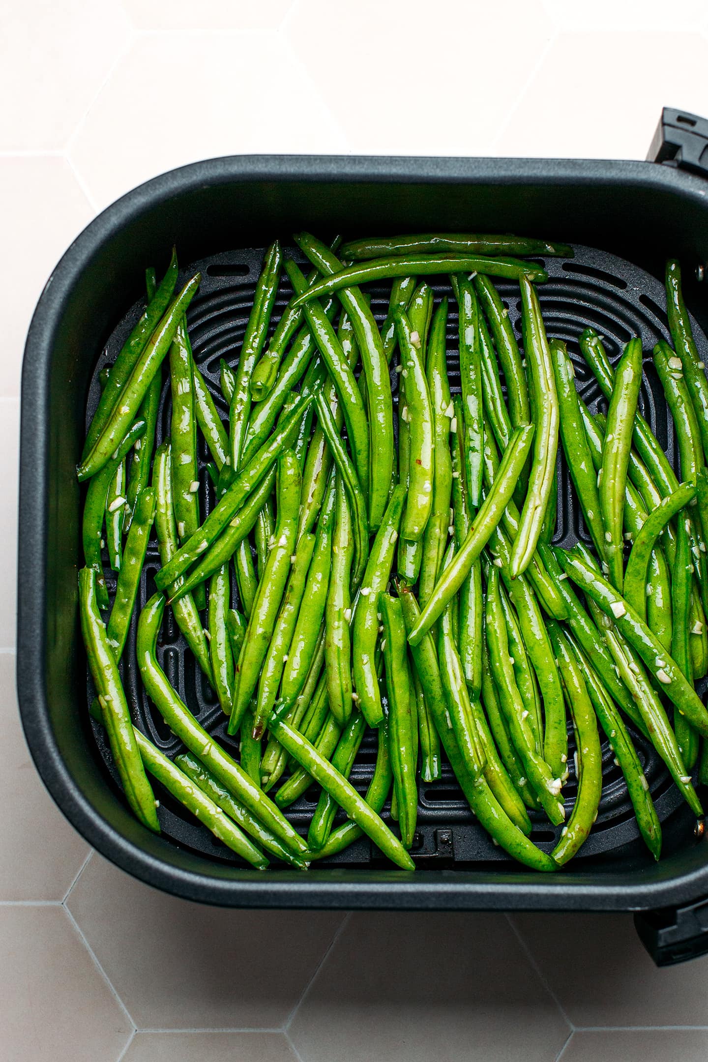 Green beans in an air fryer basket.