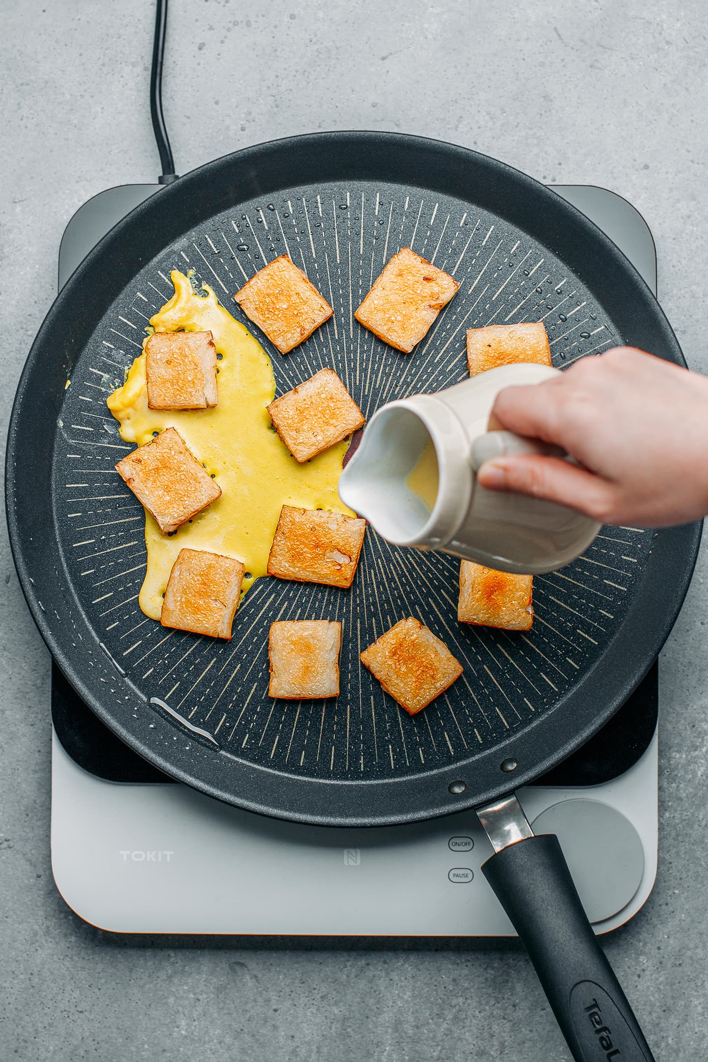 Pouring vegan egg in a skillet over rice cakes.