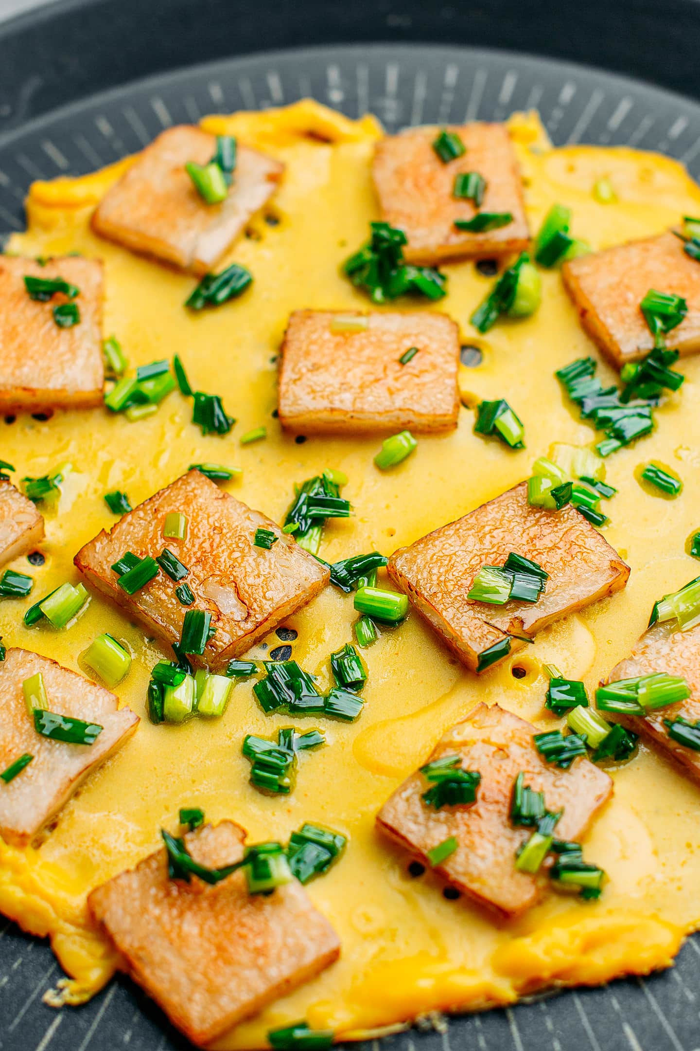 Sautéed rice cakes, omelet, and green onions in a pan.