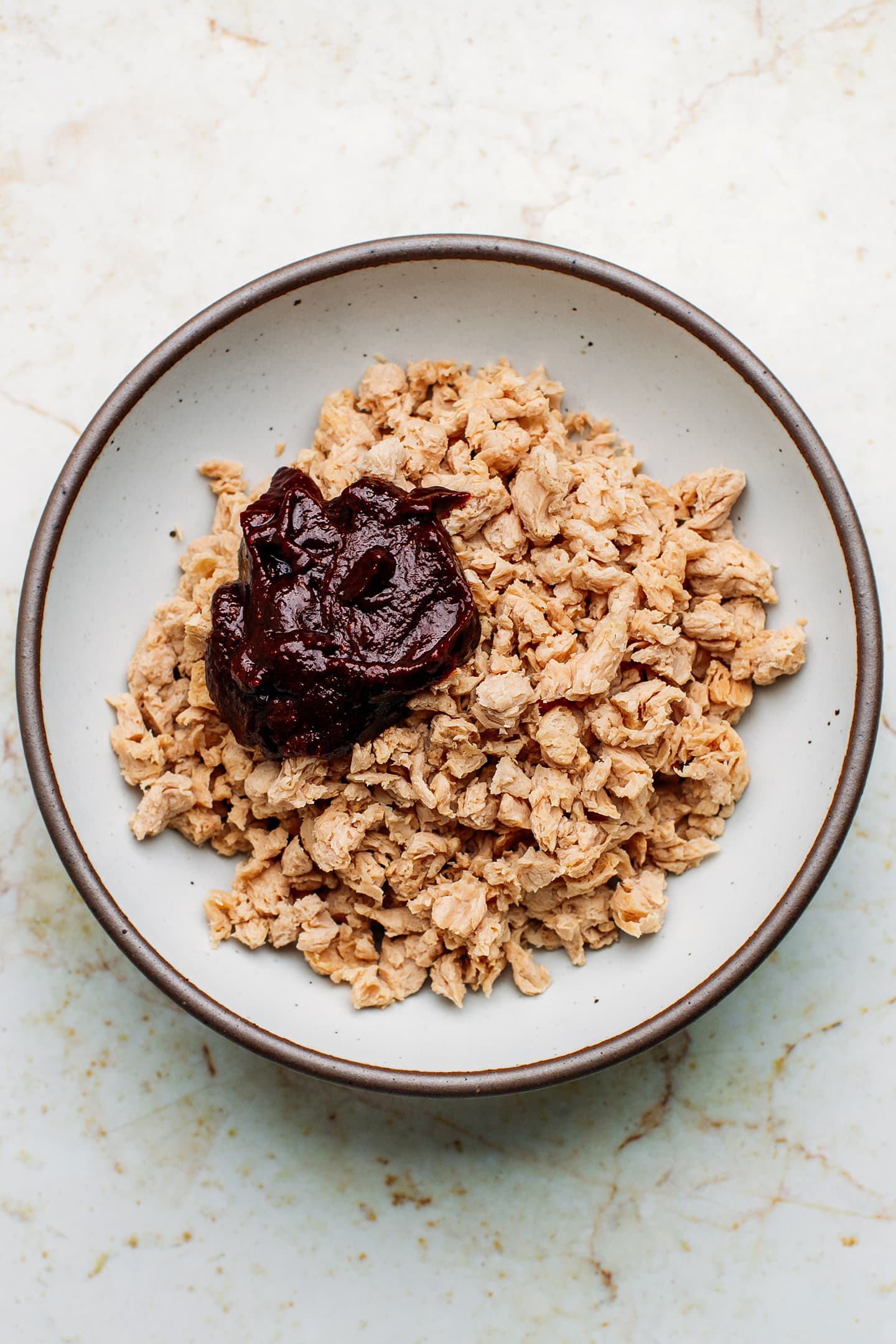 Rehydrated soy curls and tomato paste in a bowl.