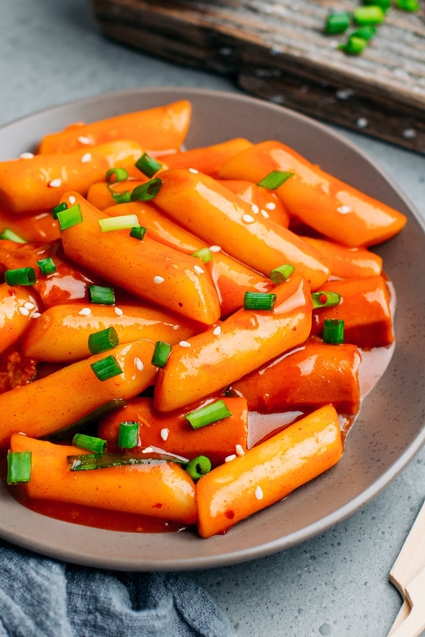 Vegan Korean rice cakes in a spicy sauce, topped with green onions.