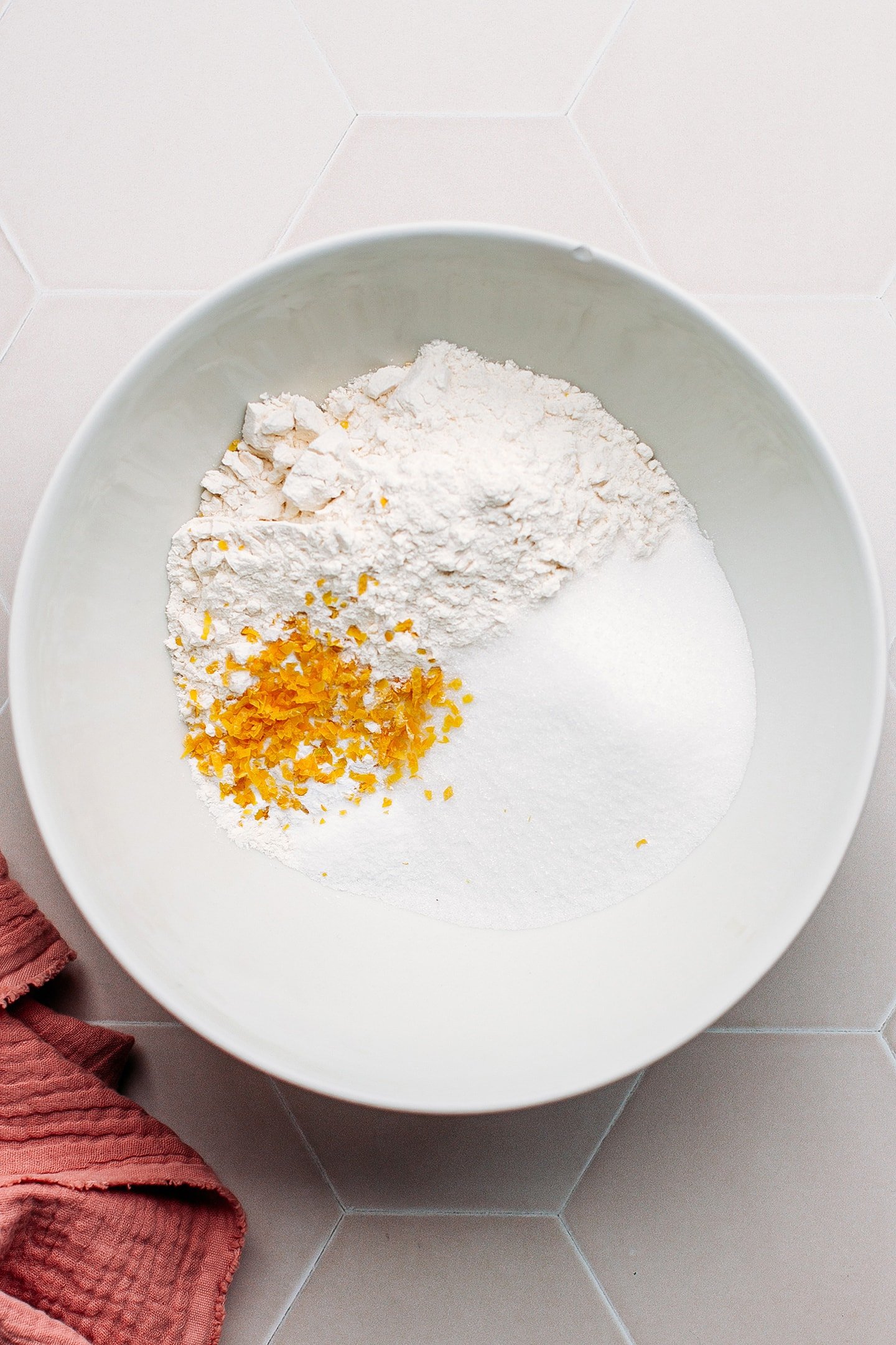 Flour, sugar, baking powder, and lemon zest in a mixing bowl.