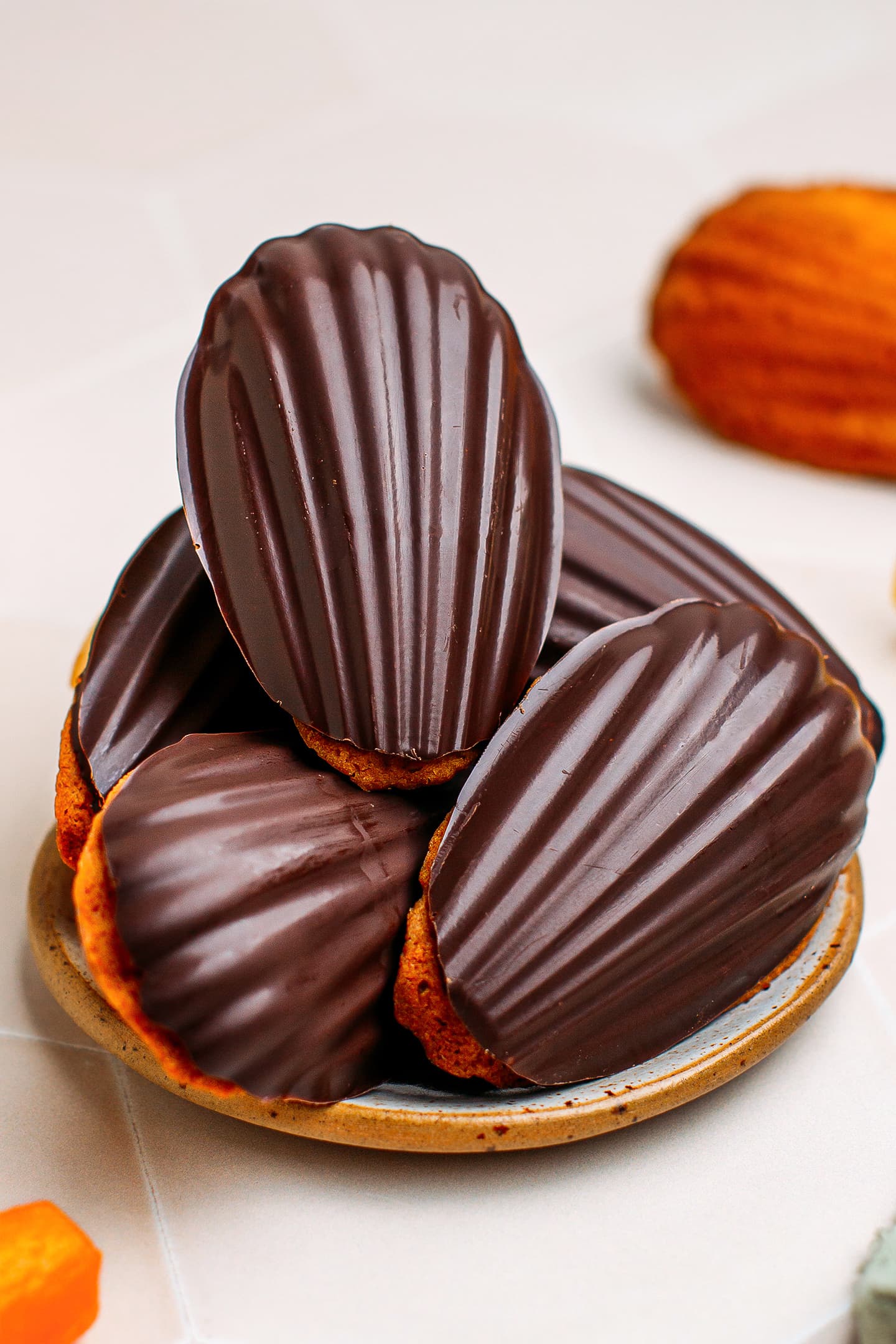 Madeleines dipped in dark chocolate on a plate.