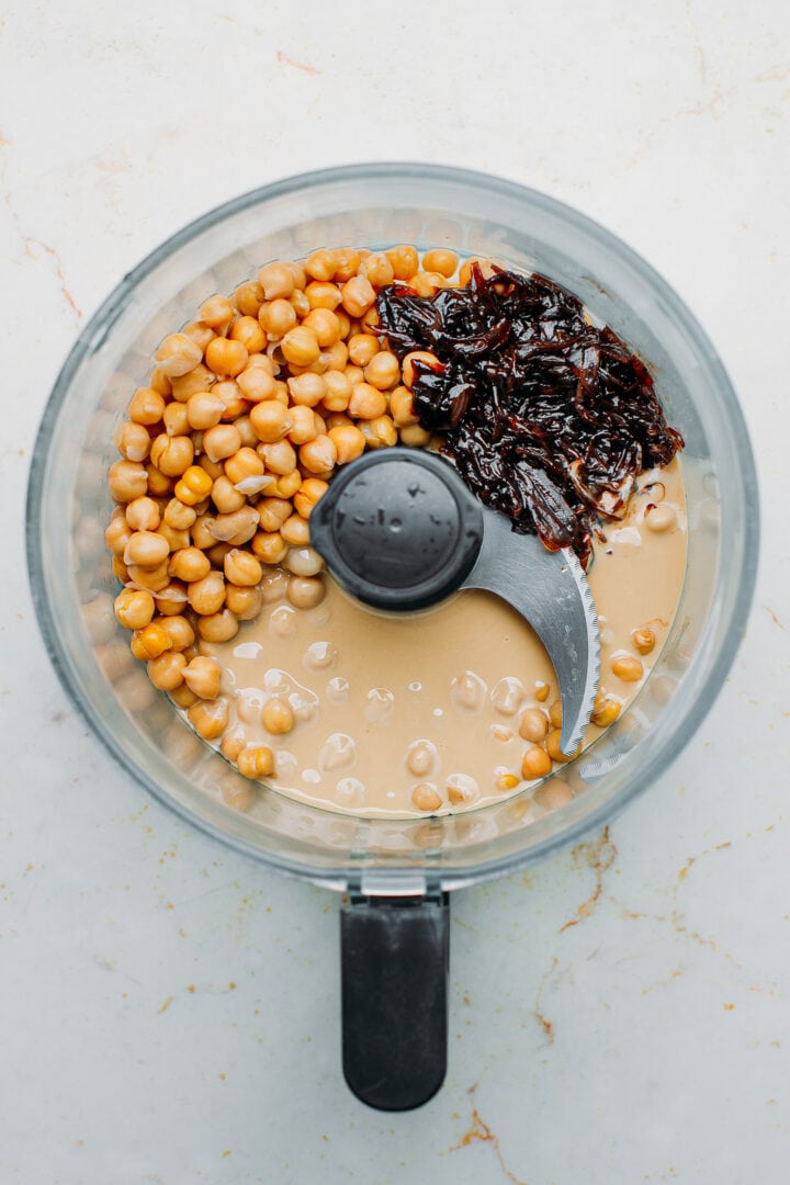 Chickpeas, tahini, garlic, and caramelized shallots in a food processor.