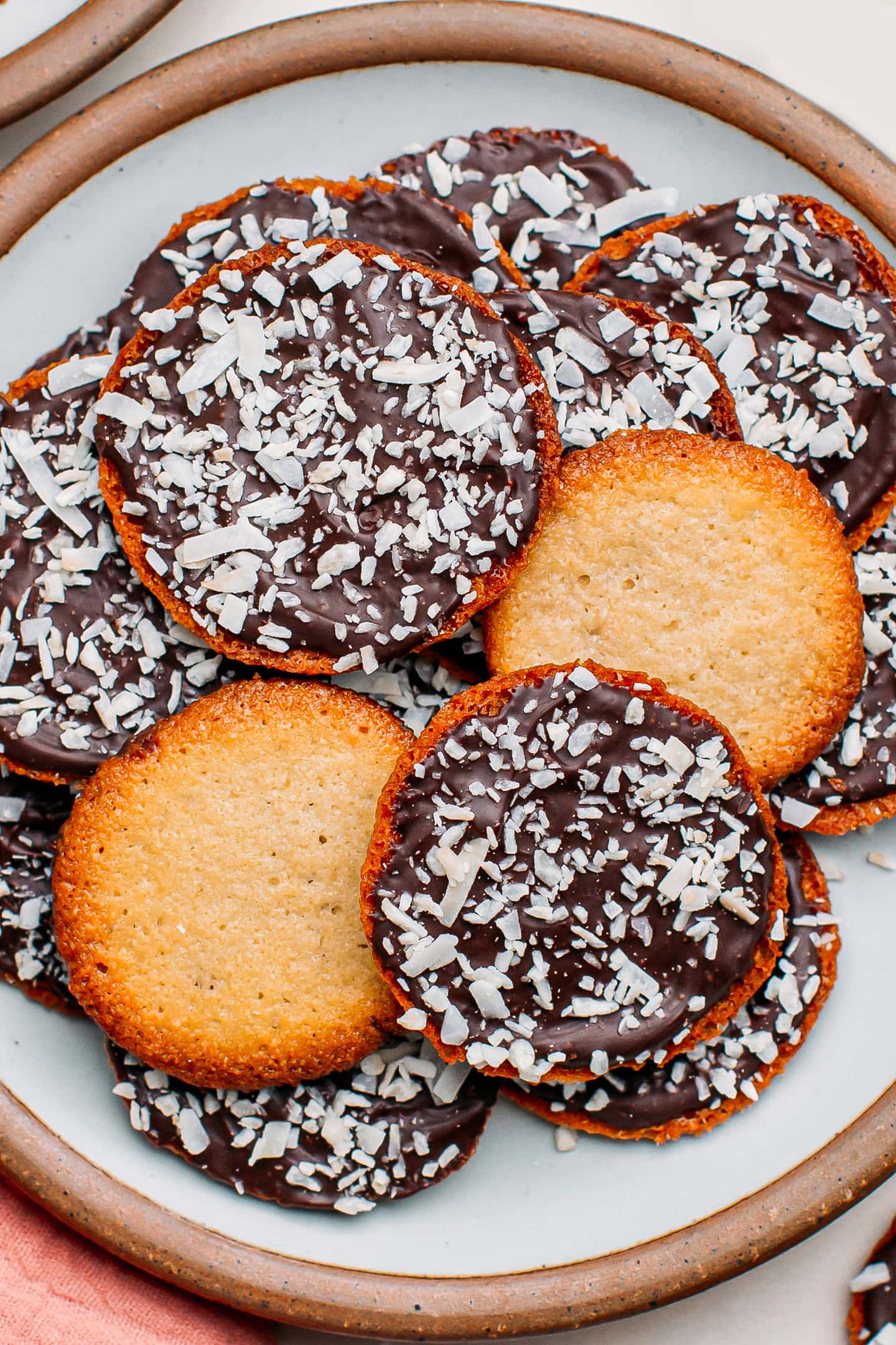 Close-up of thin cookies with dark chocolate and shredded coconut.