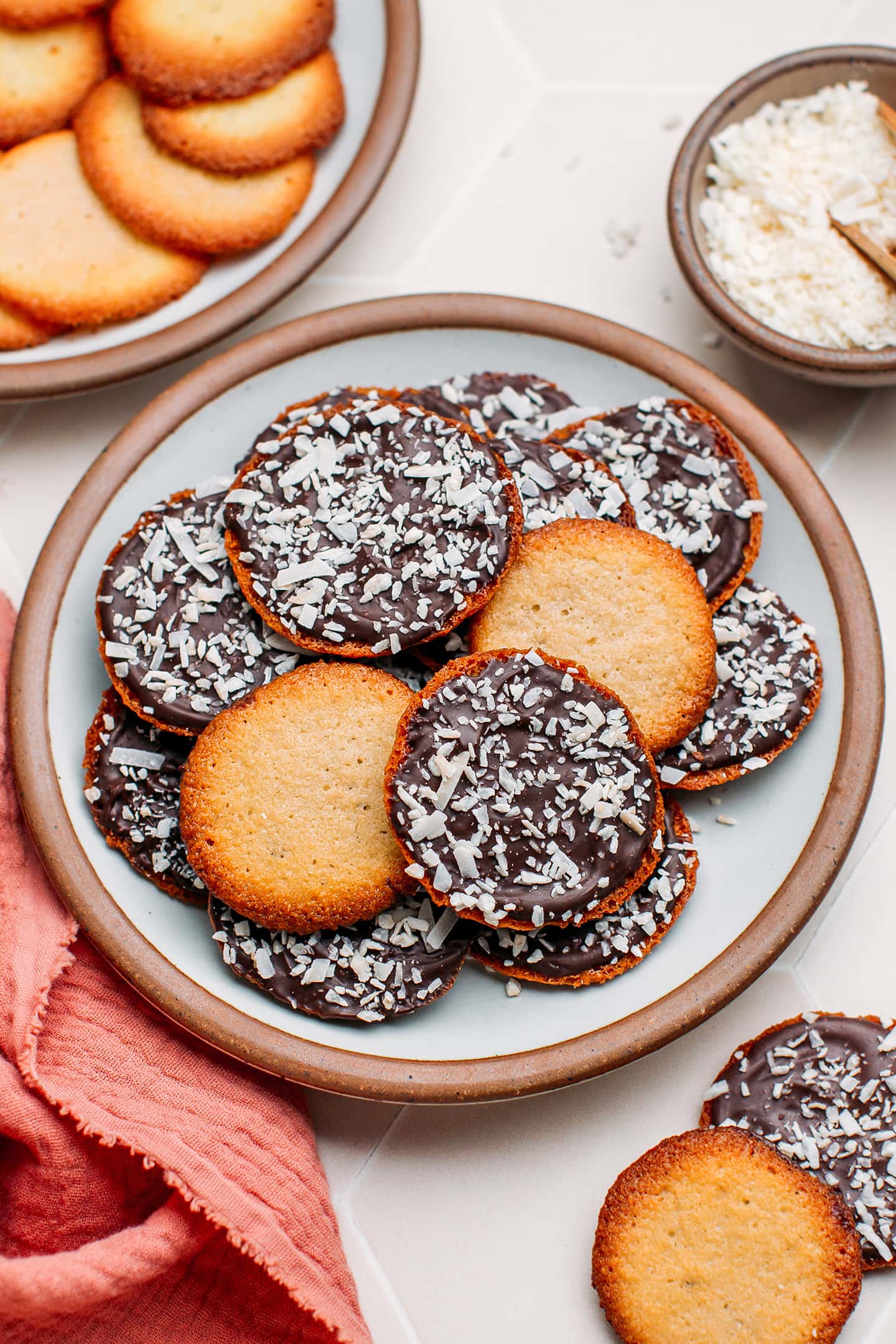 Thin cookies with dark chocolate and coconut on a small plate.