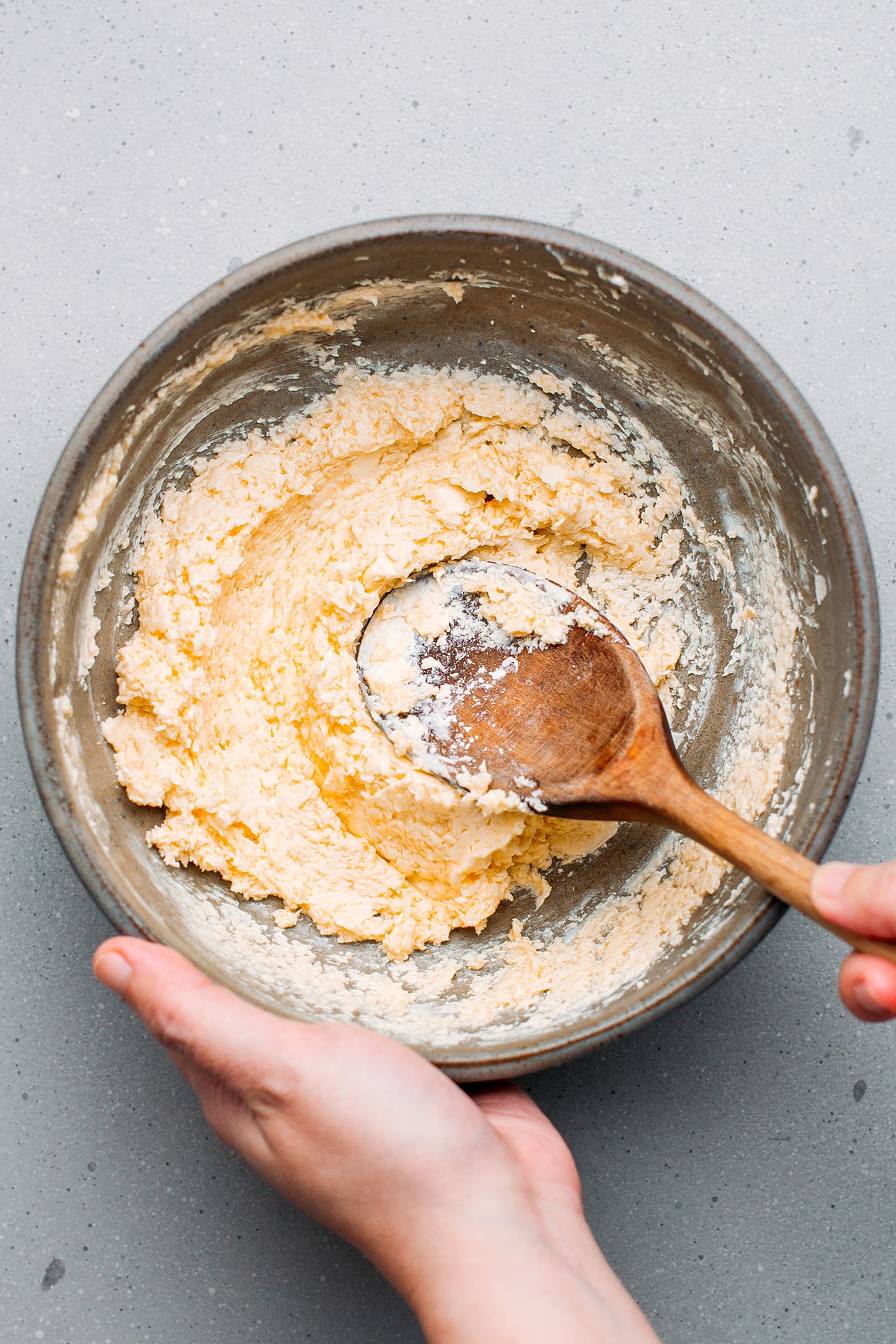 Mixing butter with powdered sugar in a bowl.