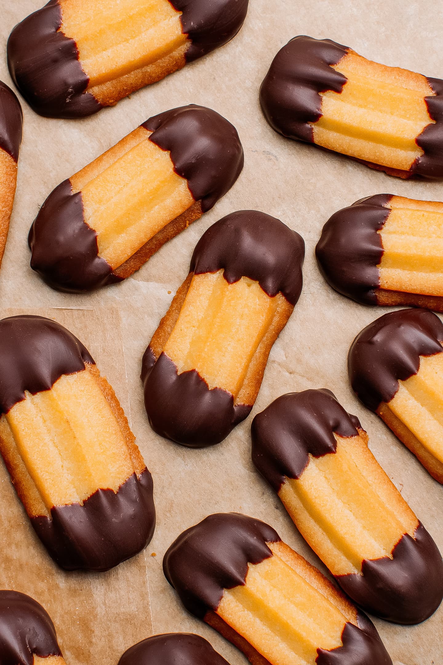 Spritz cookies dipped in dark chocolate on a baking sheet.