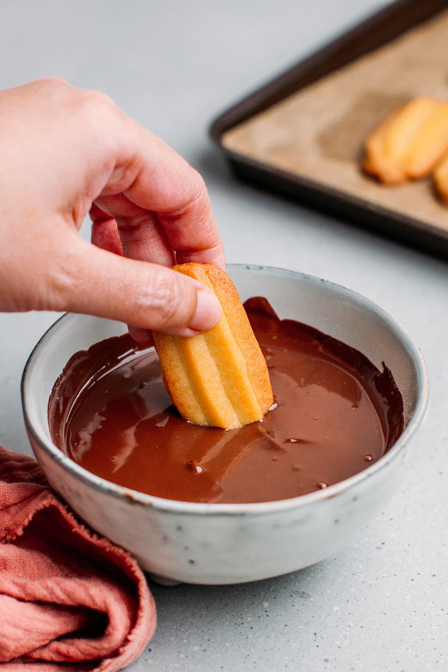 Dipping a spritz cookie in melted dark chocolate.