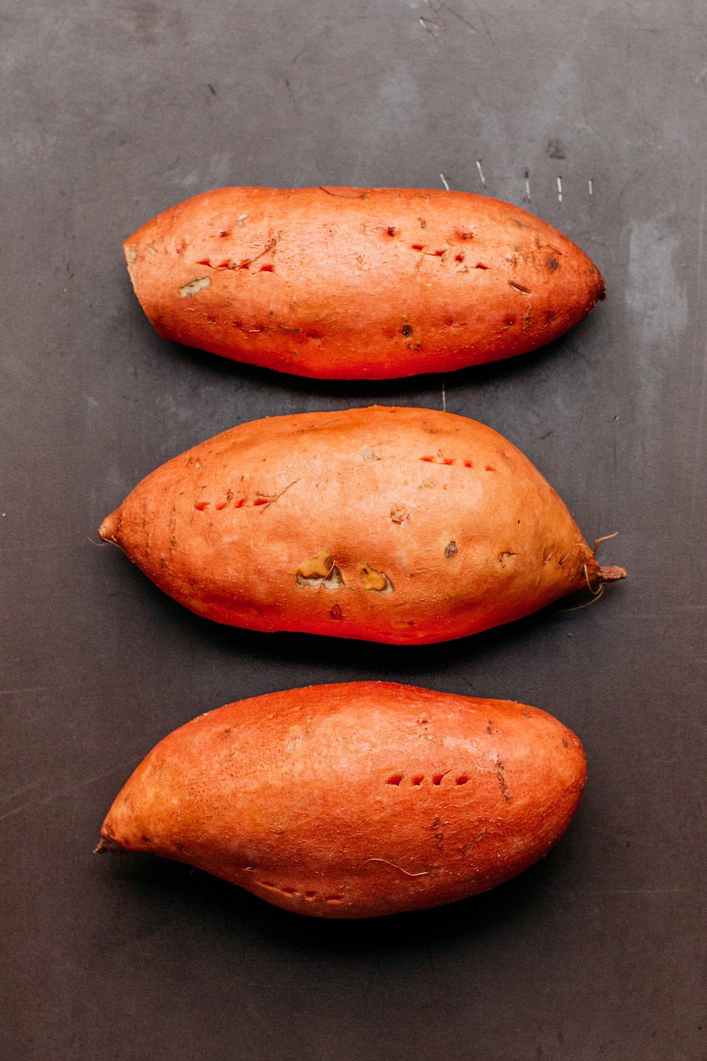 Uncooked sweet potatoes on a baking sheet.