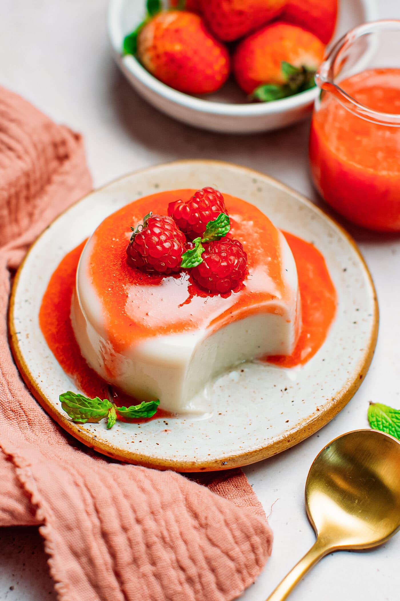 Vegan panna cotta with raspberry sauce and mint.