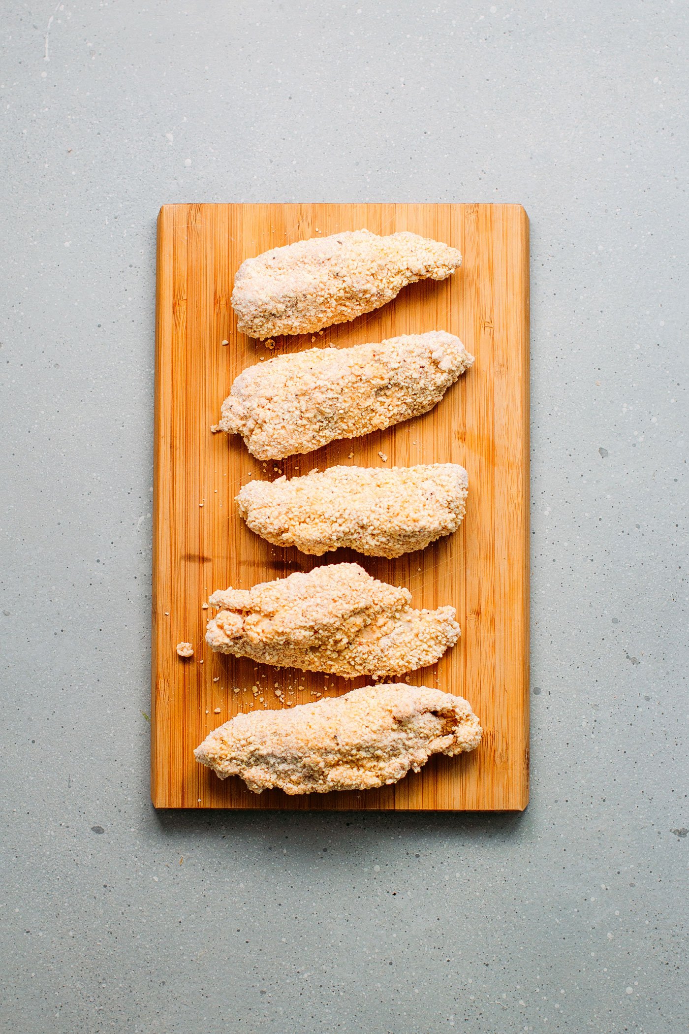 Vegan chicken nuggets before frying on a wooden board.