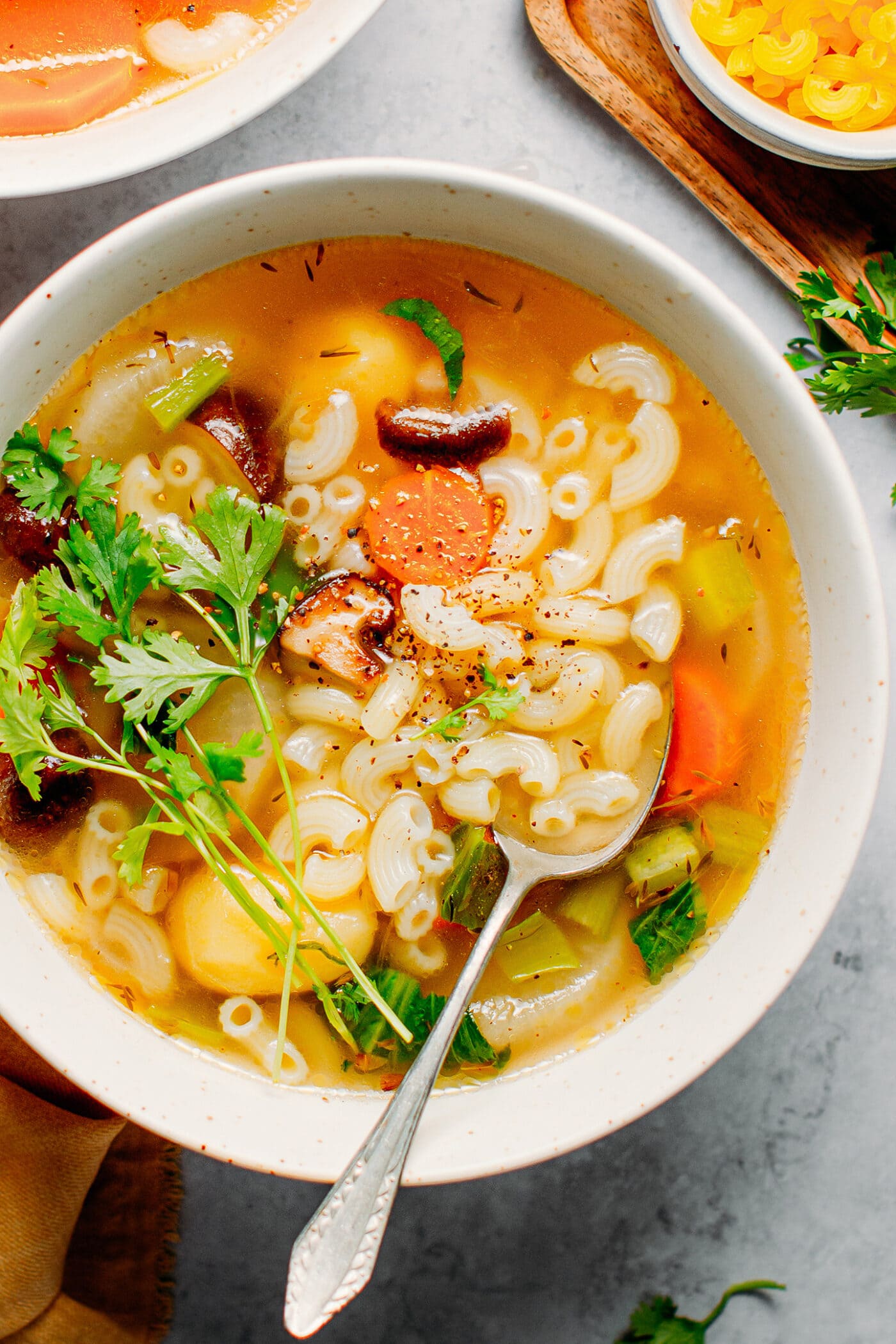 Close-up of vegan vegetable macaroni soup with carrots, potatoes, and mushrooms.