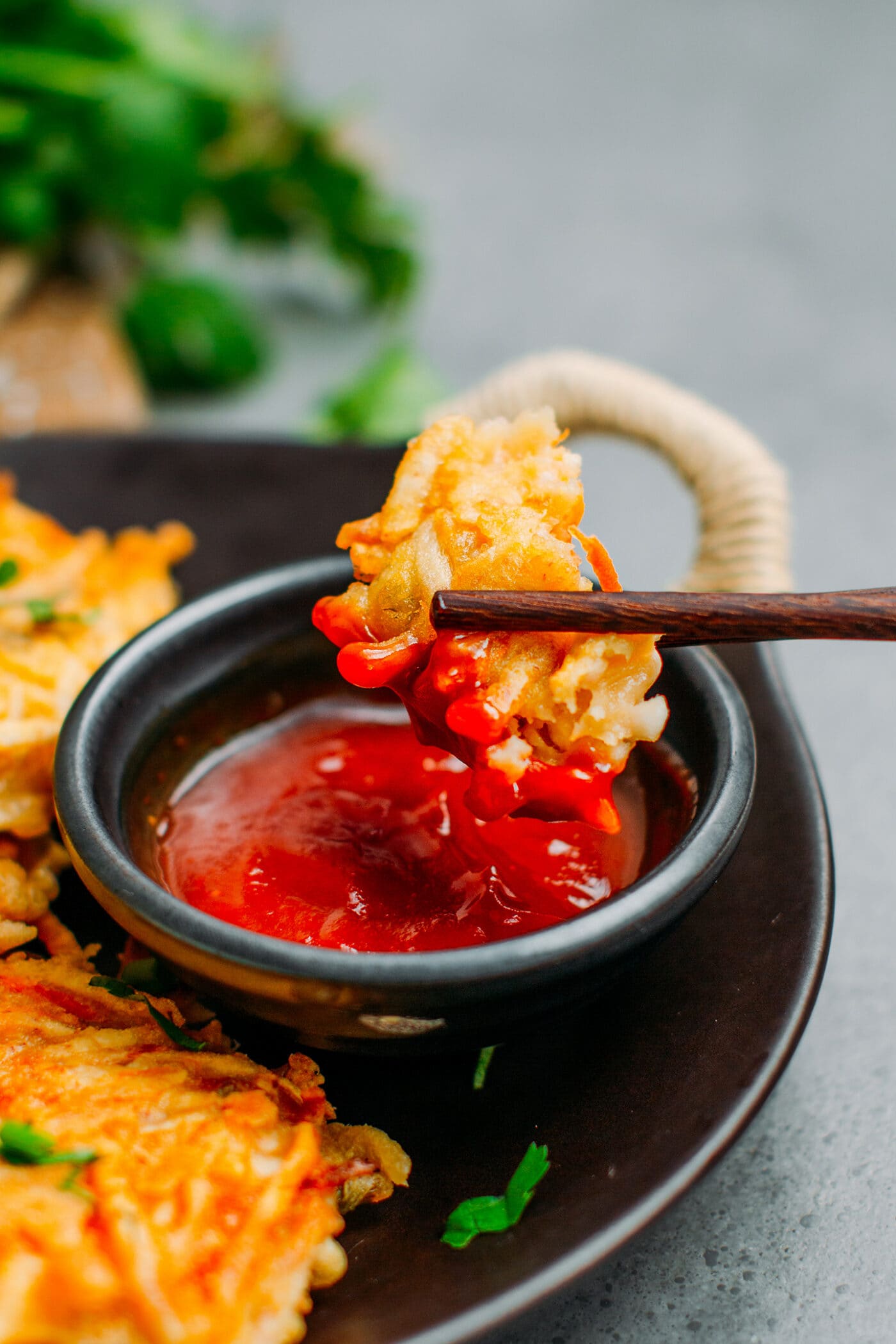 Close up of taro fritters dipped in sweet chili sauce.