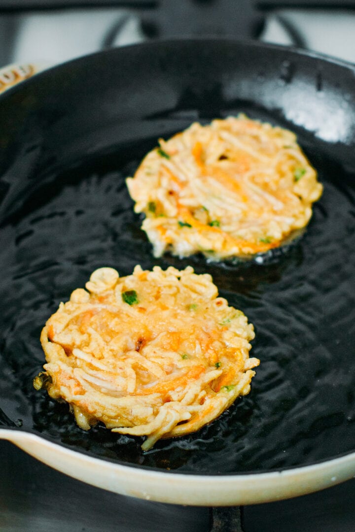 Frying taro fritters in a skillet.