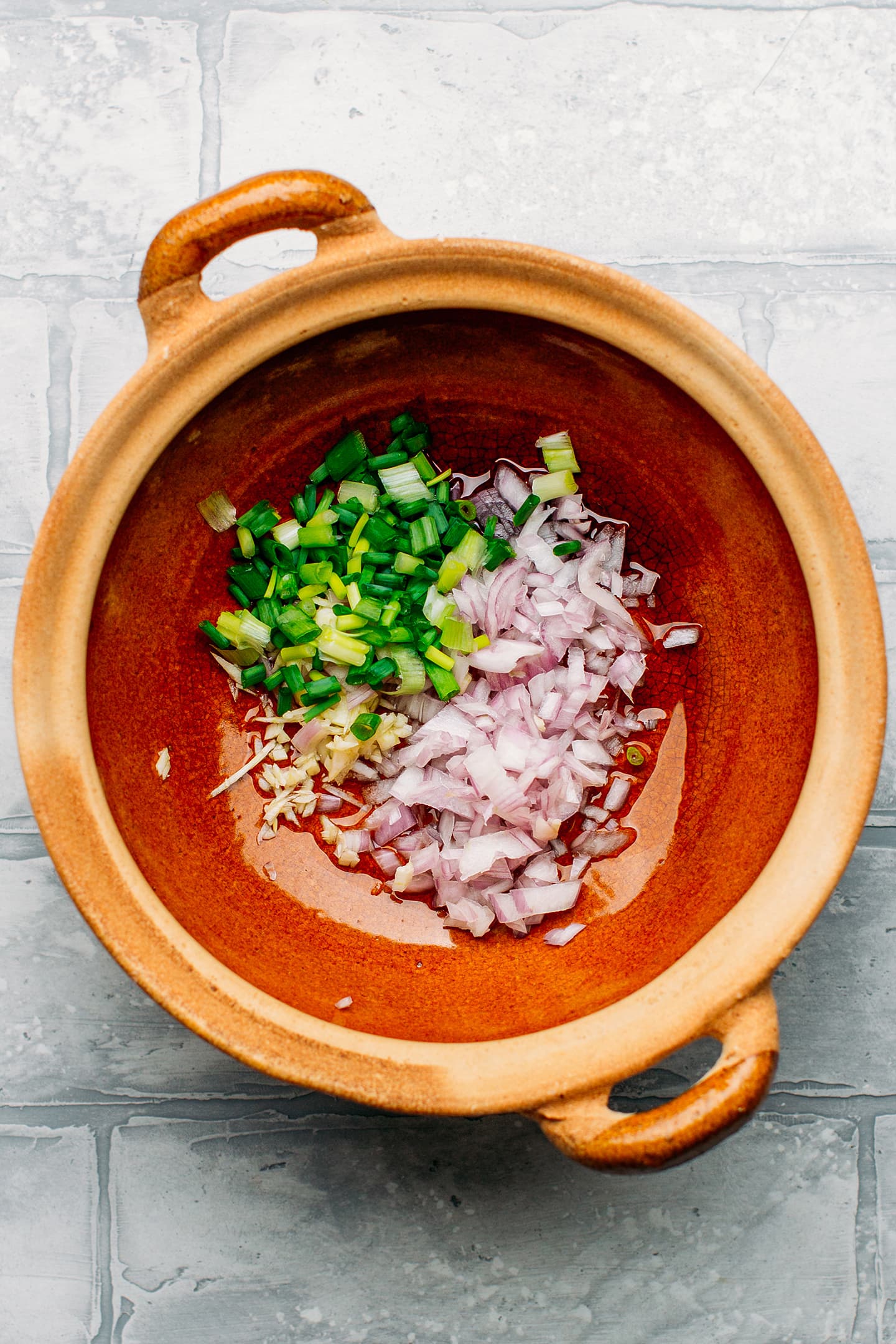 Shallots, green onions, and garlic in a clay pot.