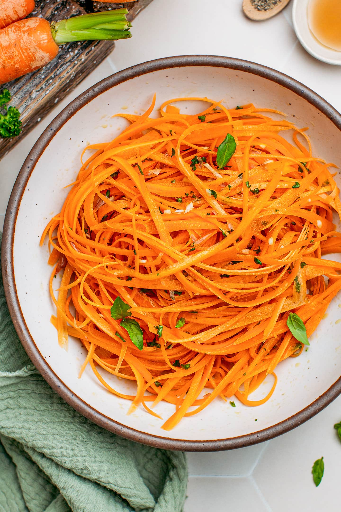 Grated carrots in a bowl with garlic and parsley.