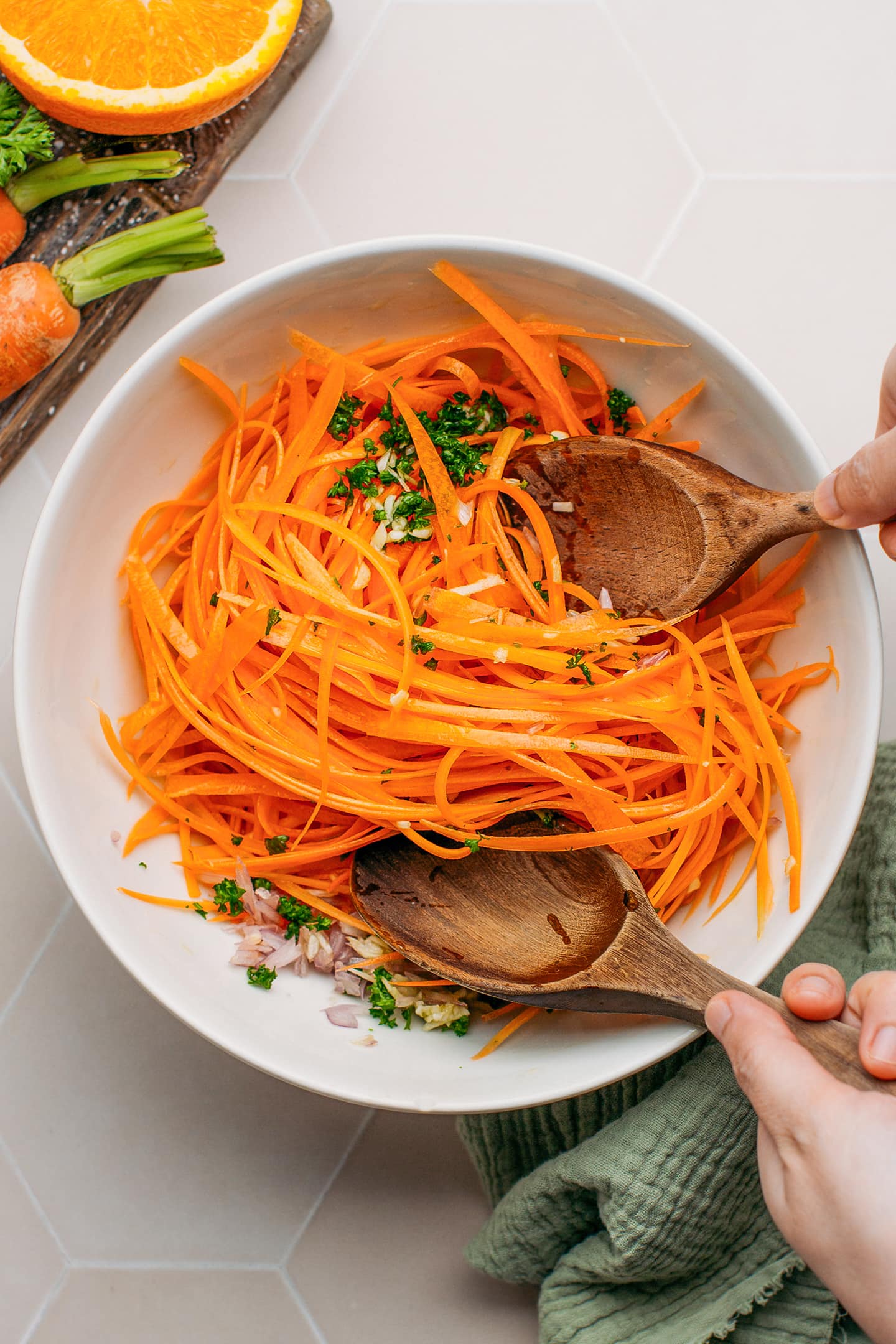Tossing grated carrots with parsley and olive oil.