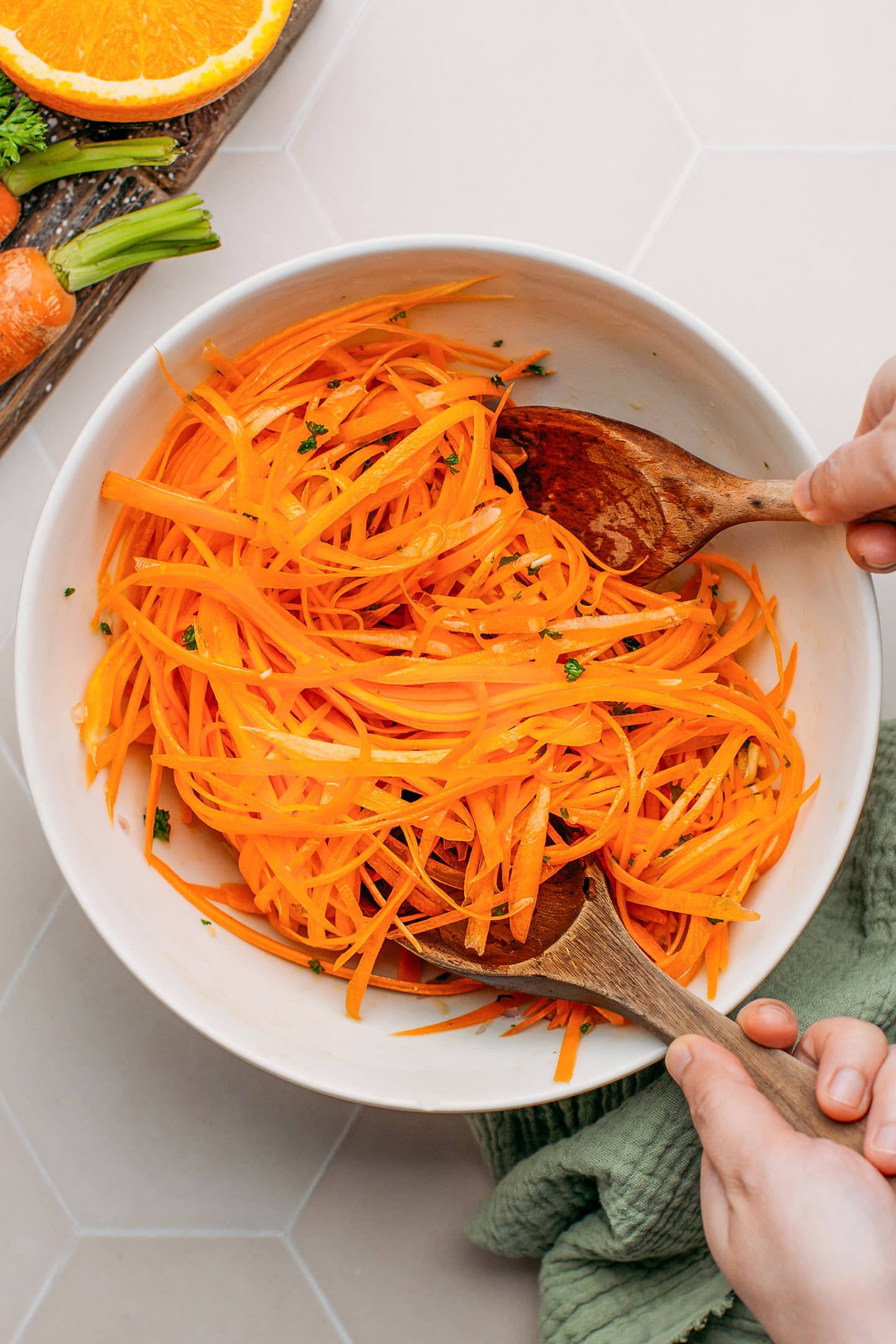 Tossing grated carrots with olive oil and lemon juice.