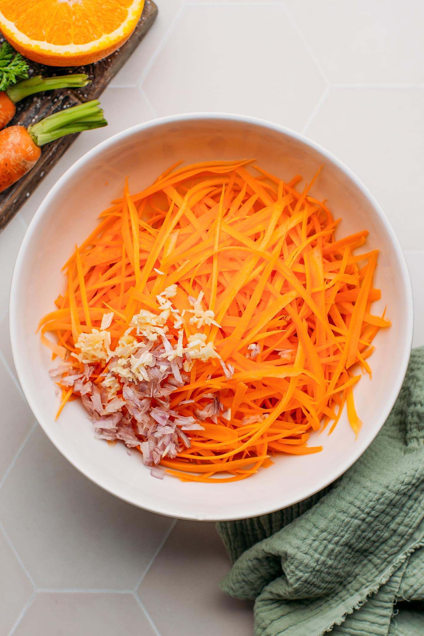 Grated carrots, garlic, and shallots in a mixing bowl.