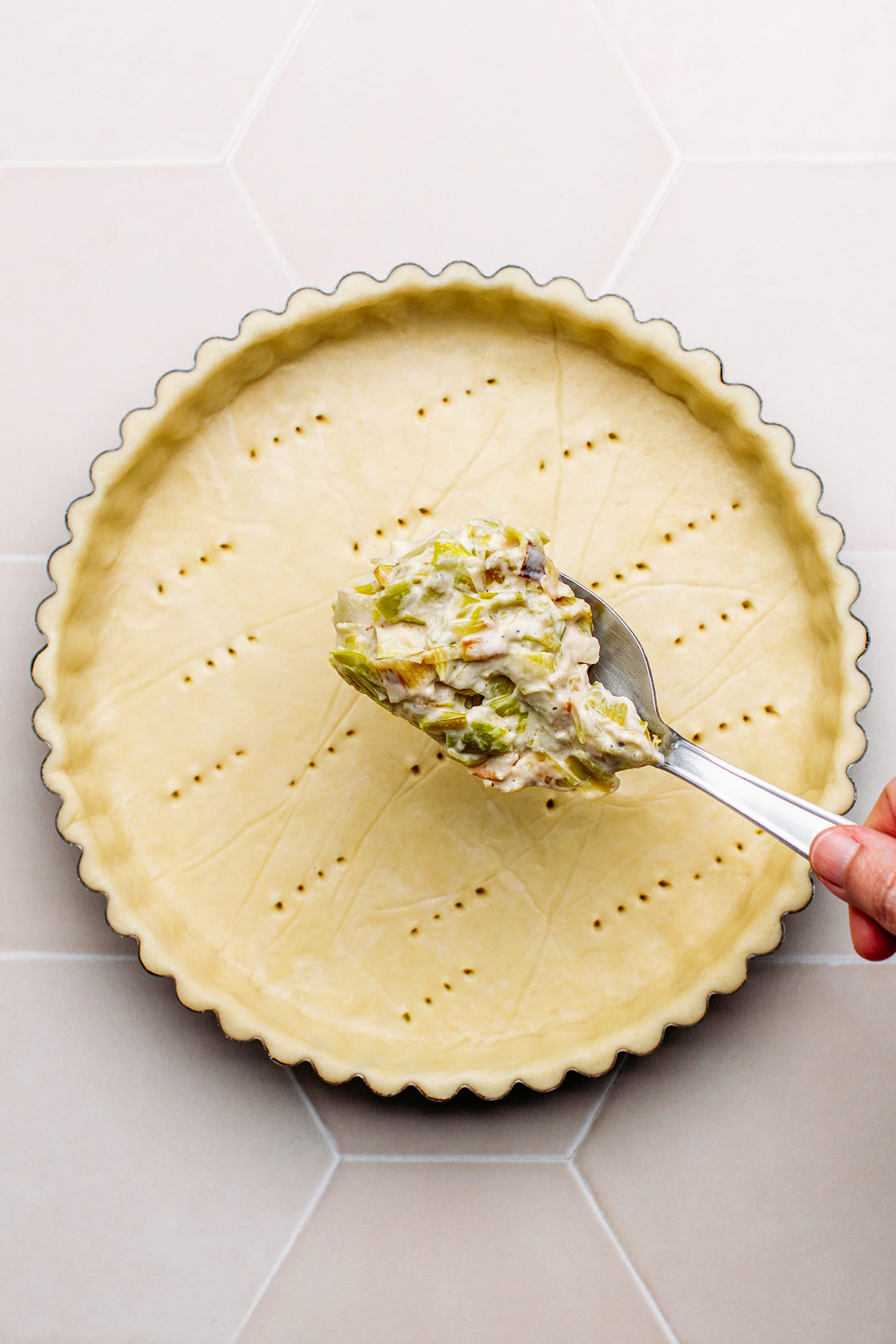 Adding leek filling on top of a pie crust.