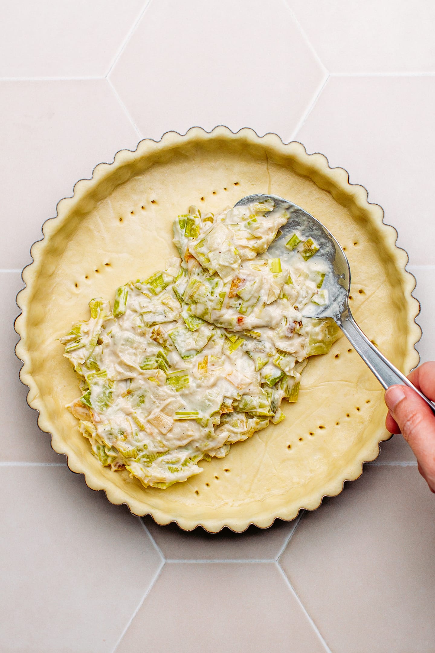 Spreading leek filling on top of a tart crust.