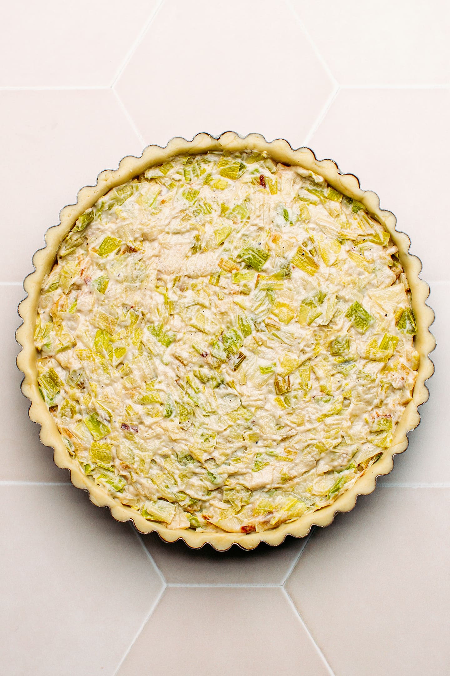 Unbaked leek tart in a pie pan.