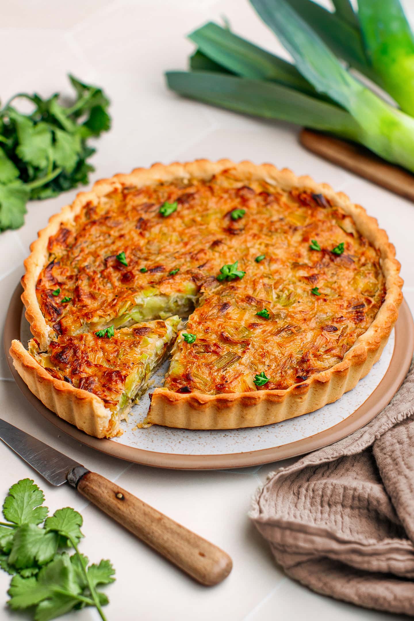 Leek tart topped with parsley on a serving plate.