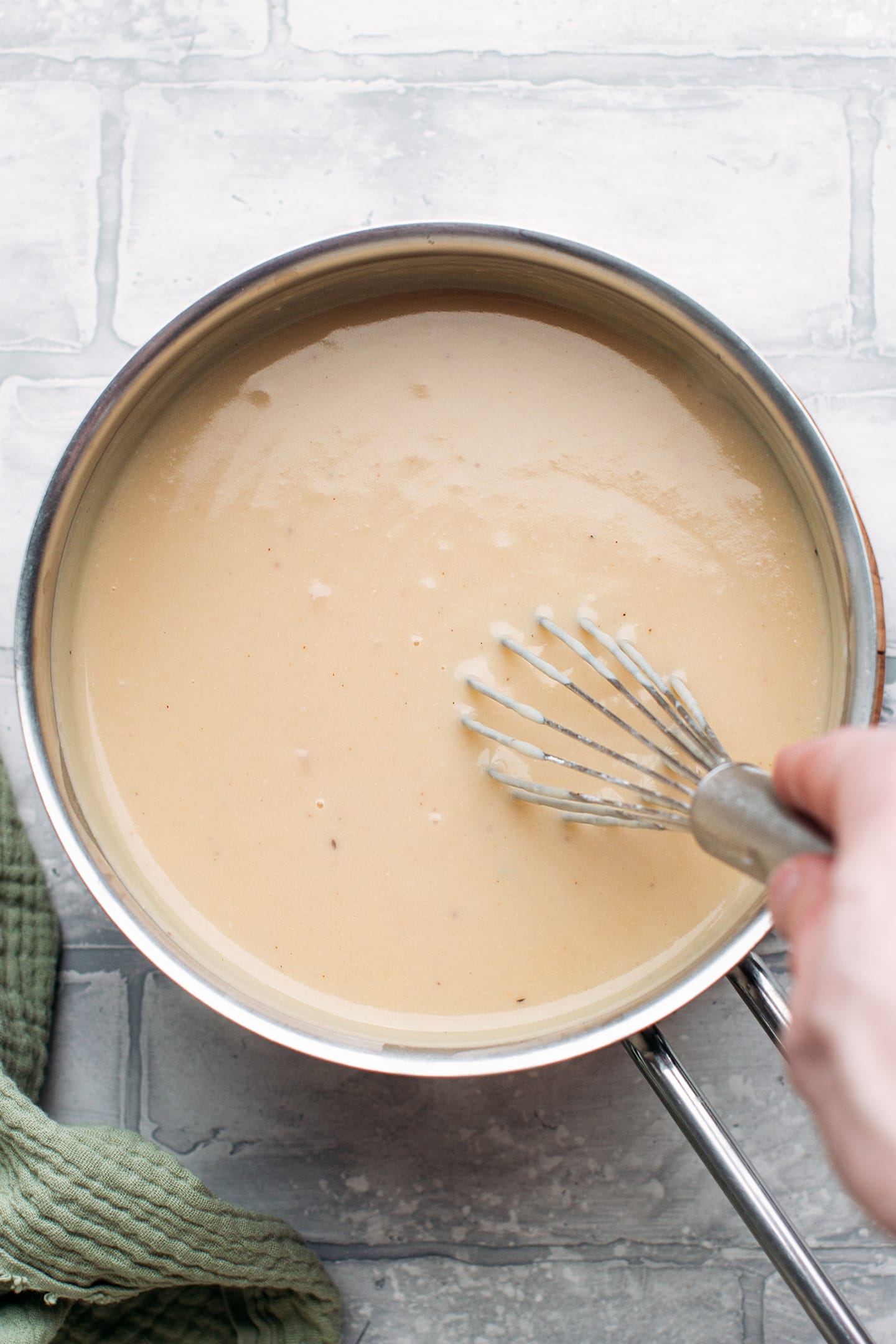 Whisking vegan bechamel in a saucepan.