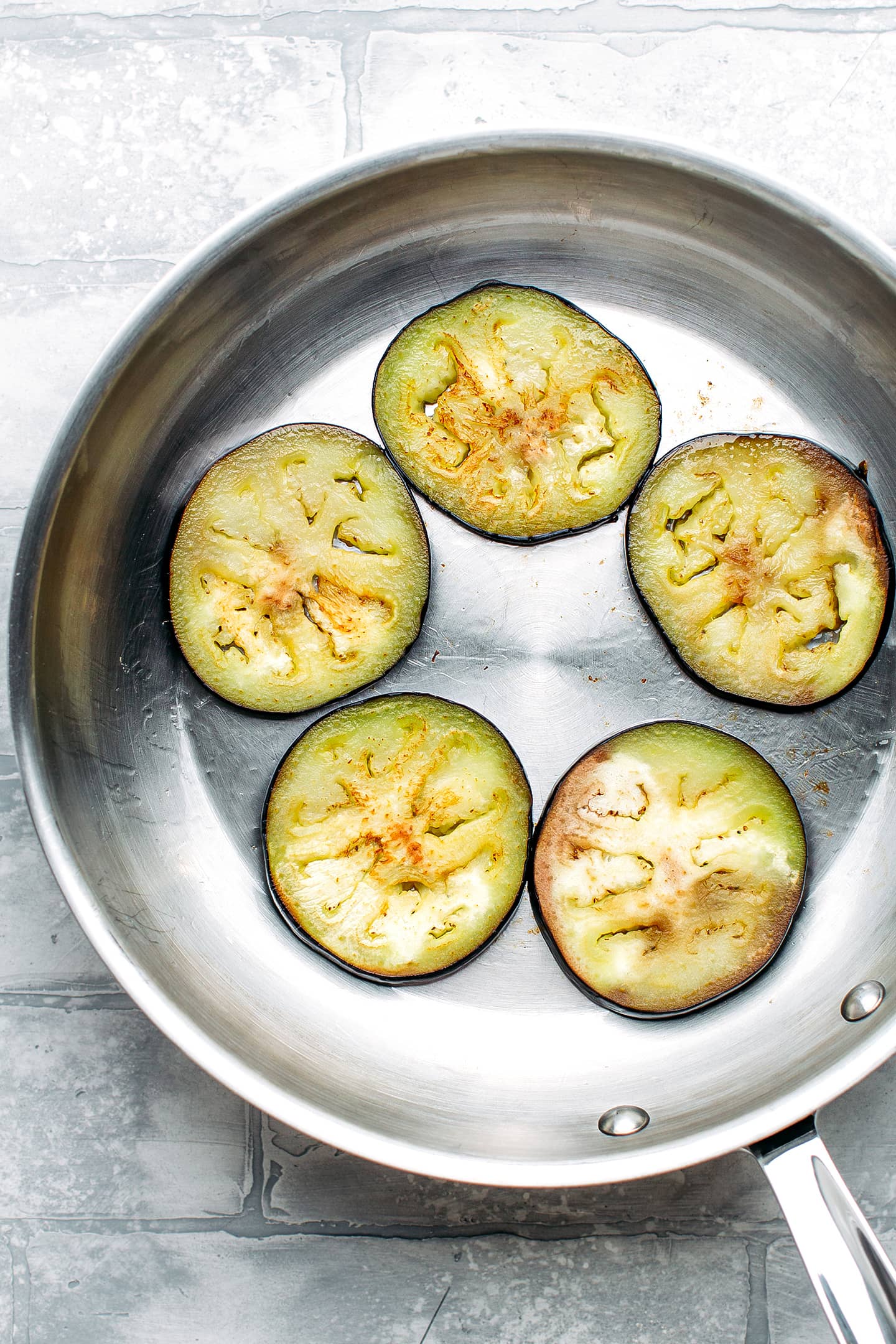 Sautéed eggplant slices in a skillet.