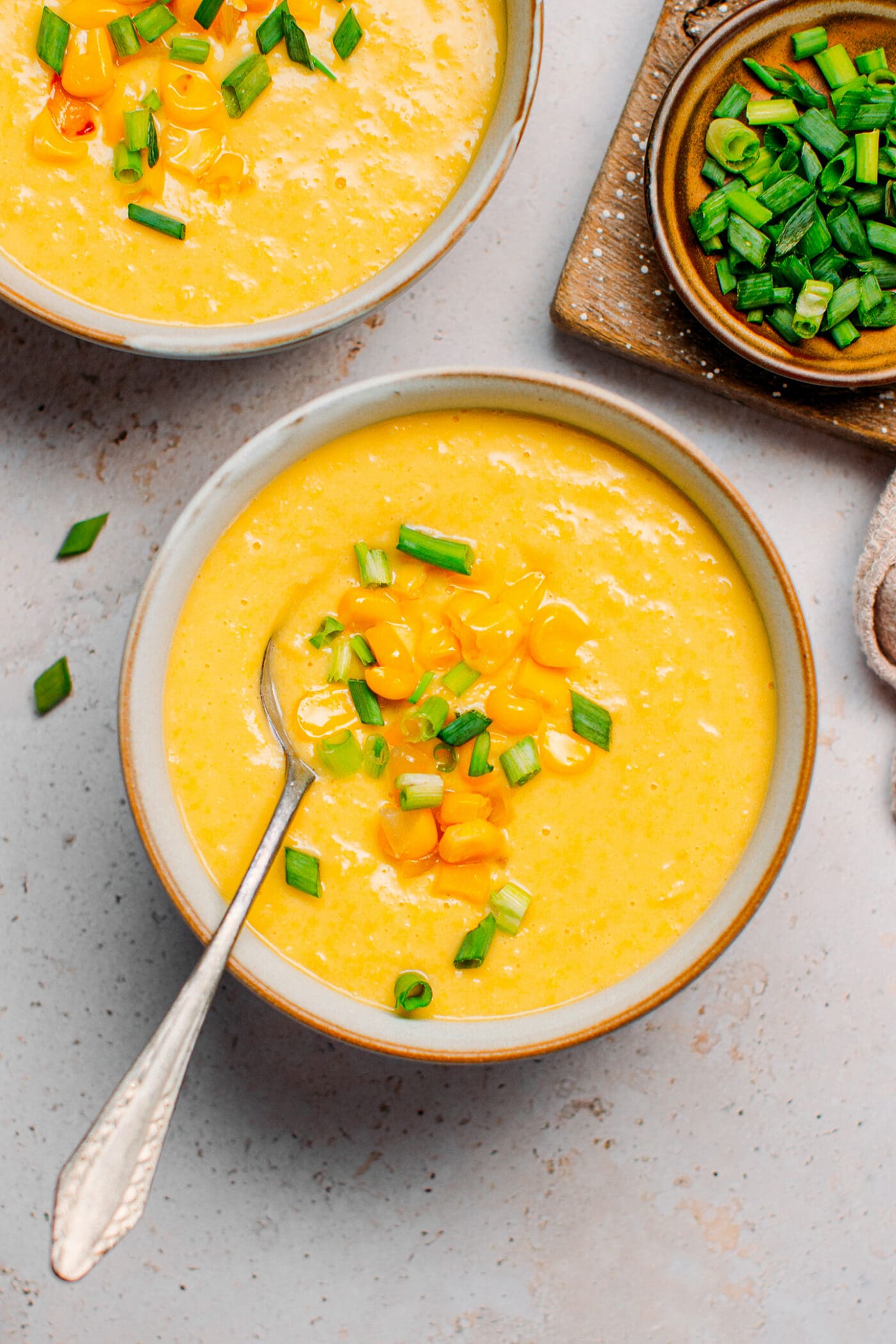 Bowls of vegan corn soup with green onions.