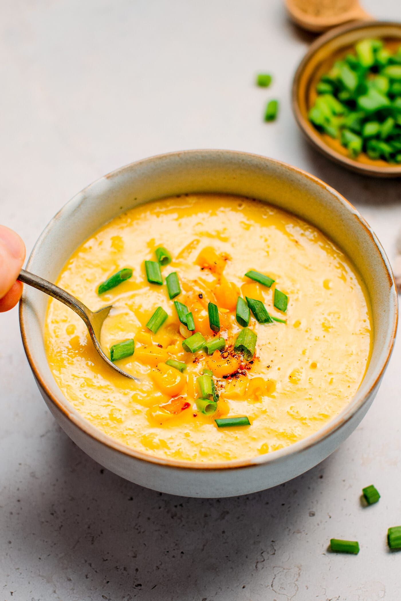Vegan corn soup topped with sautéed corn and green onions.