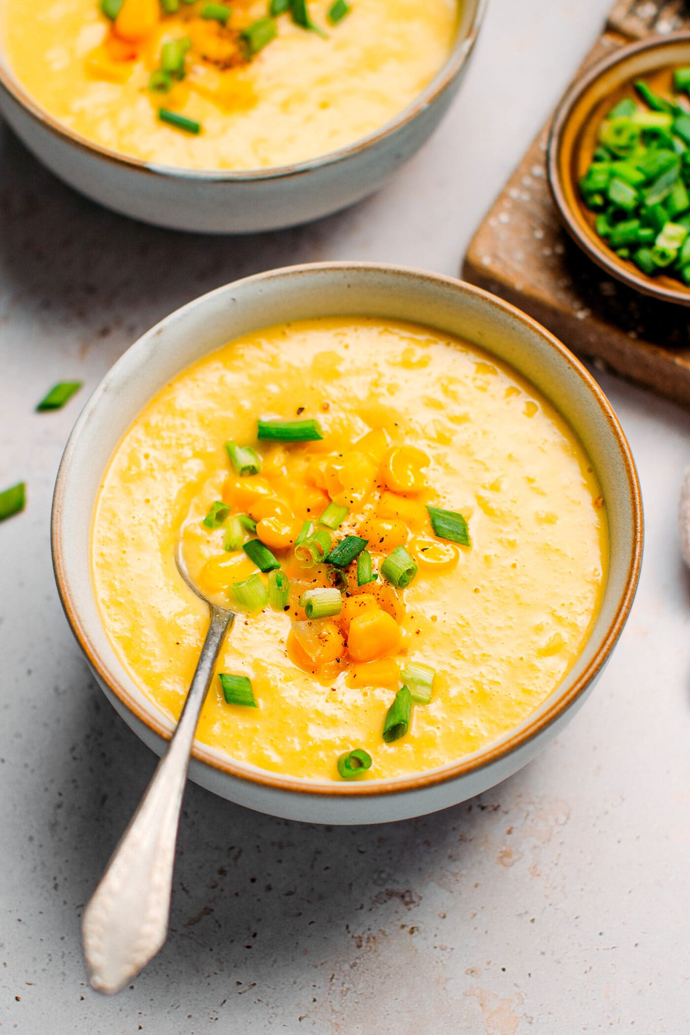 Bowl of vegan corn soup topped with sautéed corn and green onions.