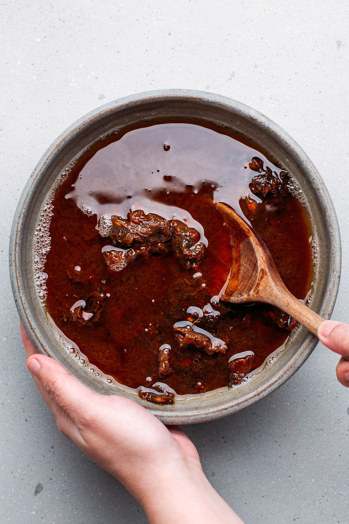 Stirring tamarind with water in a bowl.