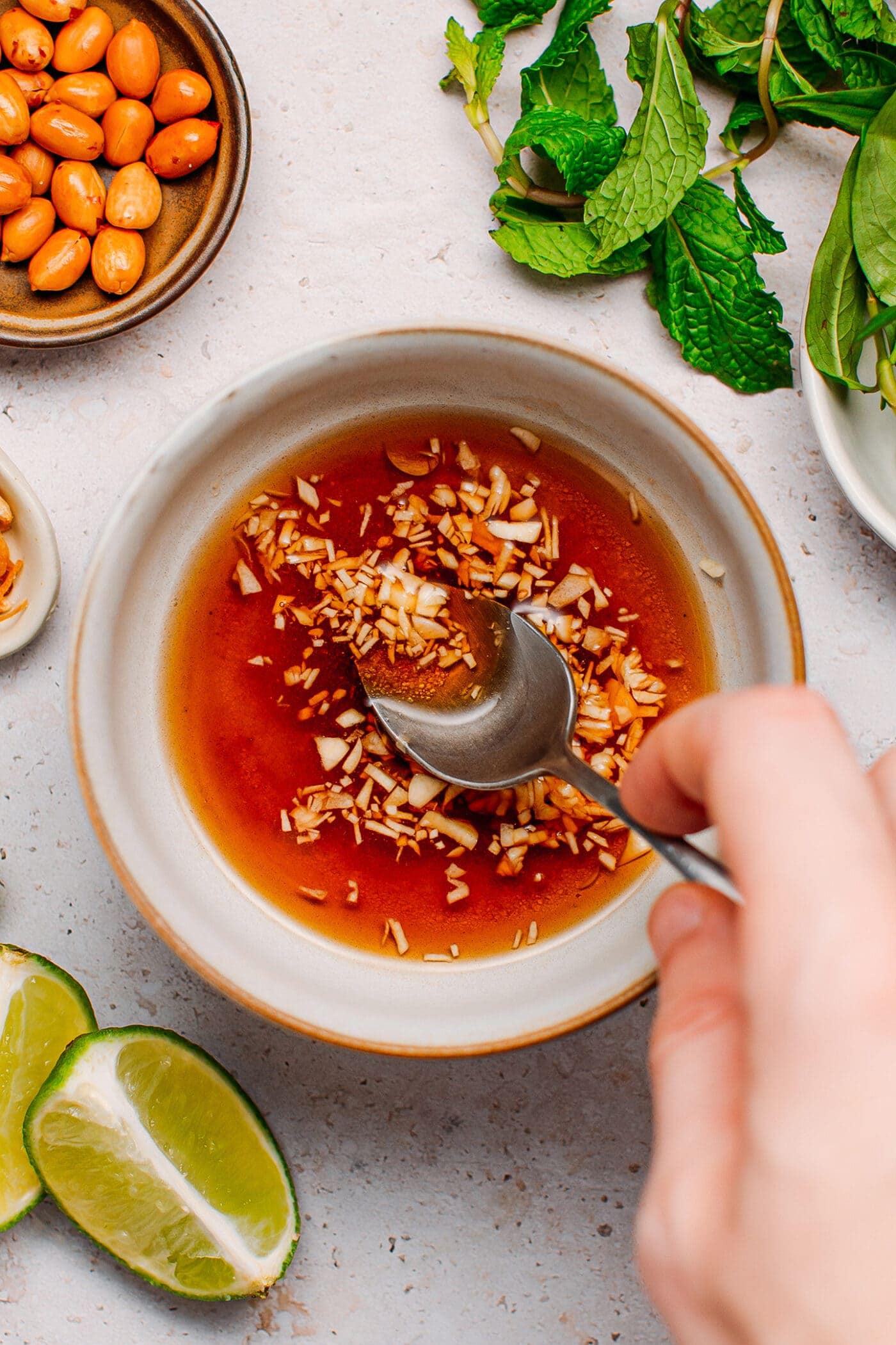 Stirring vegan fish sauce, sugar, and garlic in a bowl.