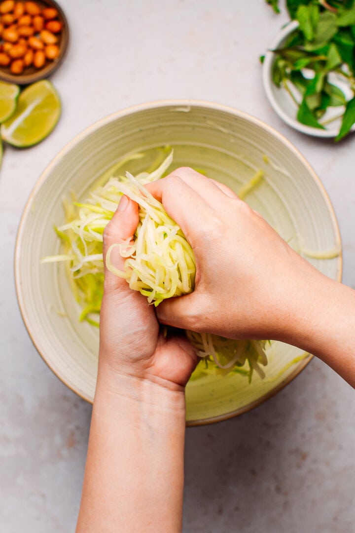 Squeezing shredded green papaya.