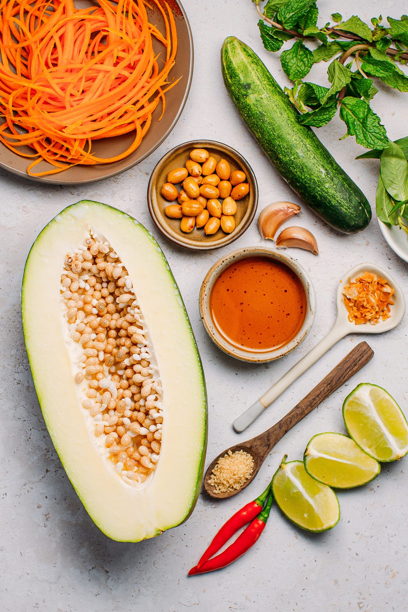Ingredients like green papaya, cucumber, fish sauce, peanuts, and lime.