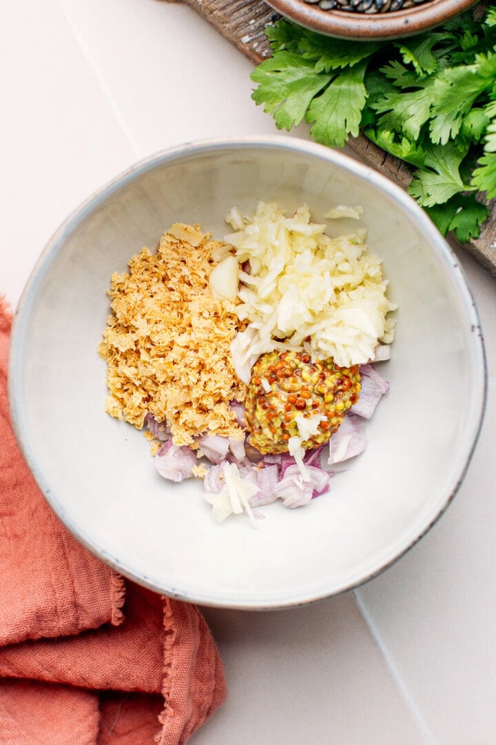 Garlic, shallots, mustard, and nutritional yeast in a bowl.