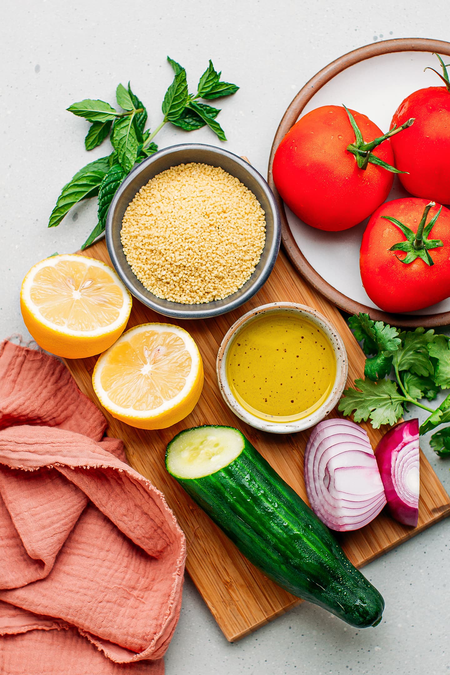 Ingredients like couscous, tomatoes, lemon, olive oil, and cucumbers.