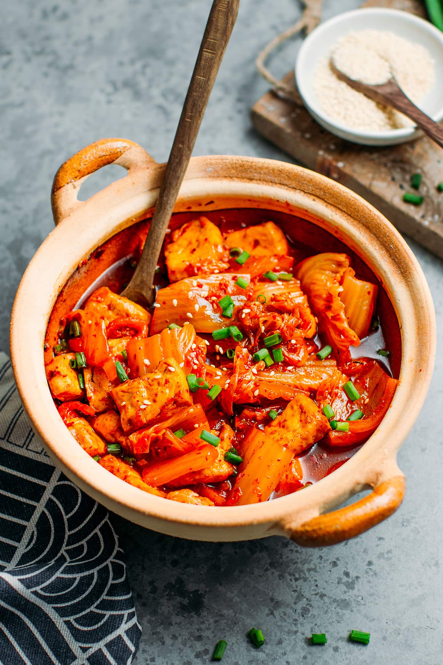 Kimchi stew in a clay pot, with tofu and green onions.