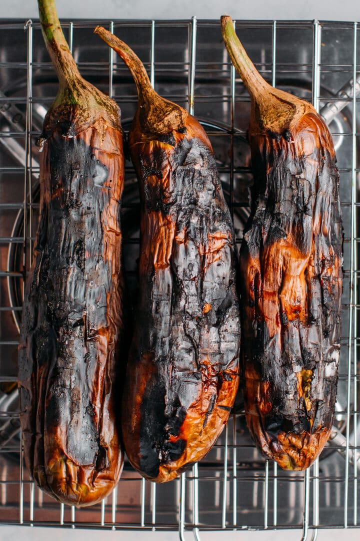 Charred eggplants on a grilling basket.