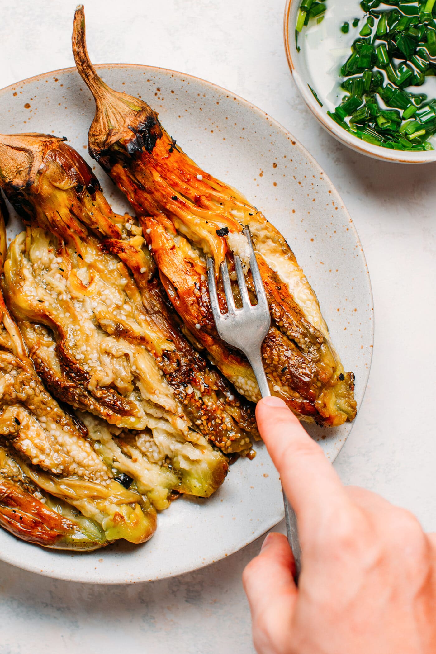 Mashing grilled eggplants with a fork.