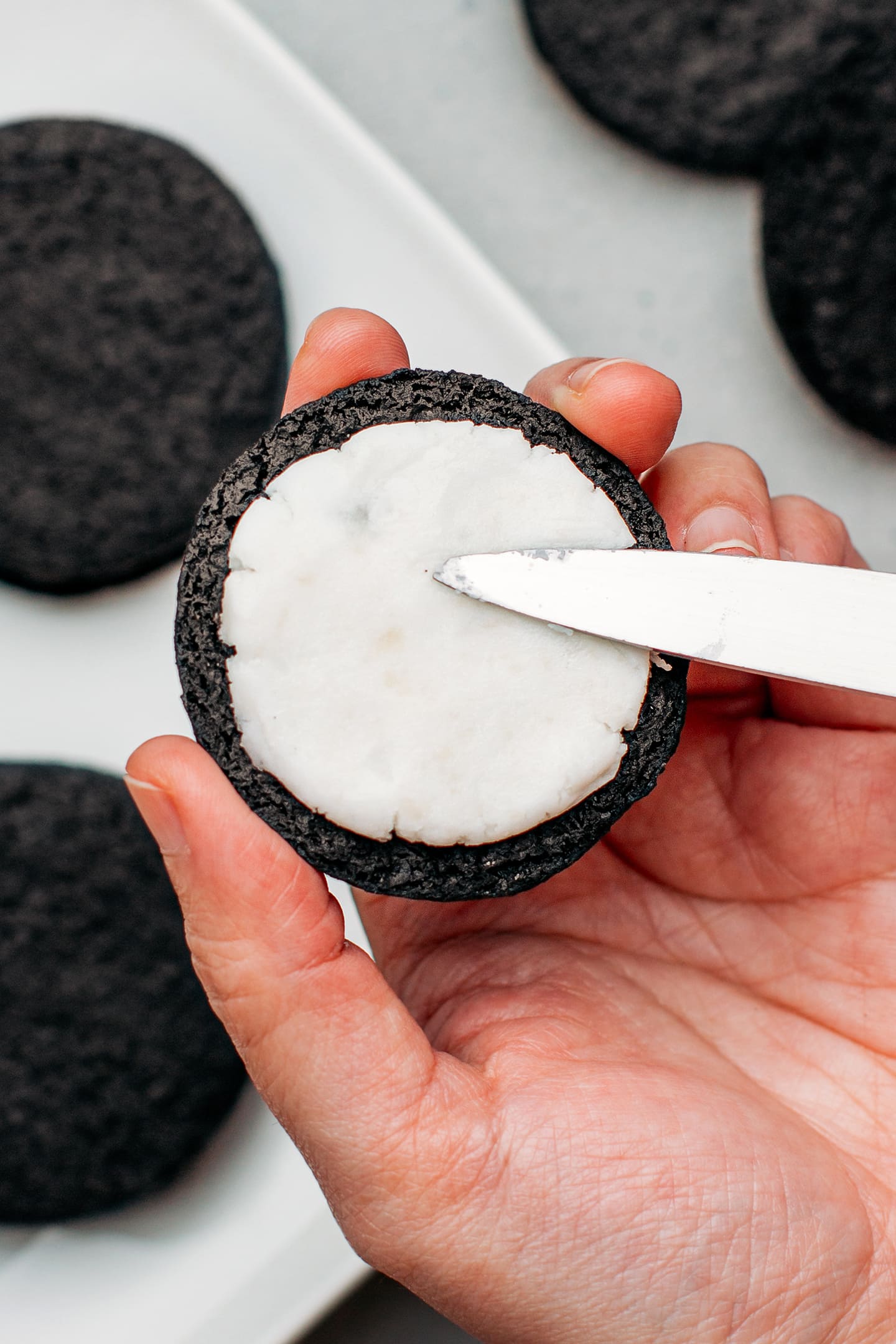 Spreading vanilla filling on a chocolate cookie.