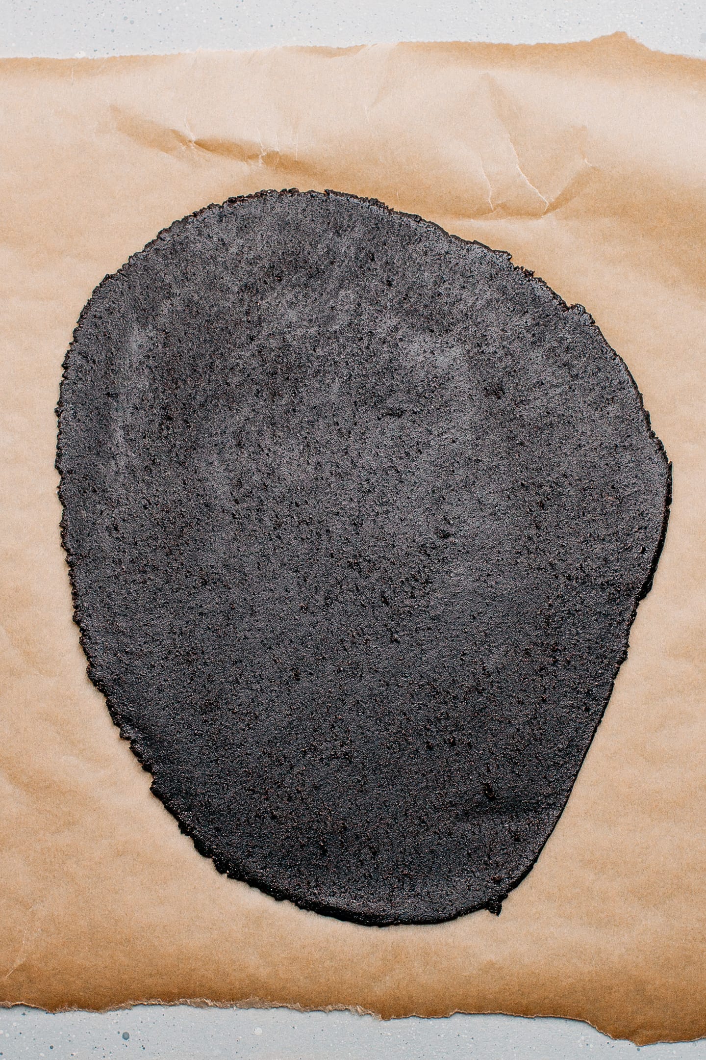 Flattened cooking dough on a piece of parchment paper.