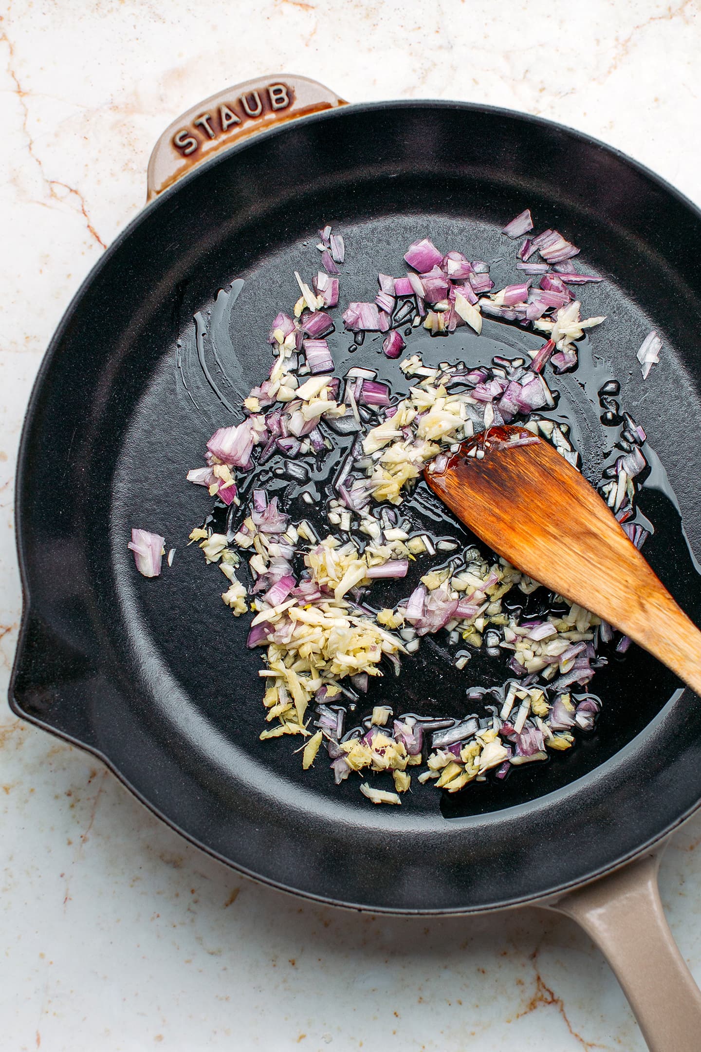 Sautéed ginger, shallots, and garlic in a skillet.