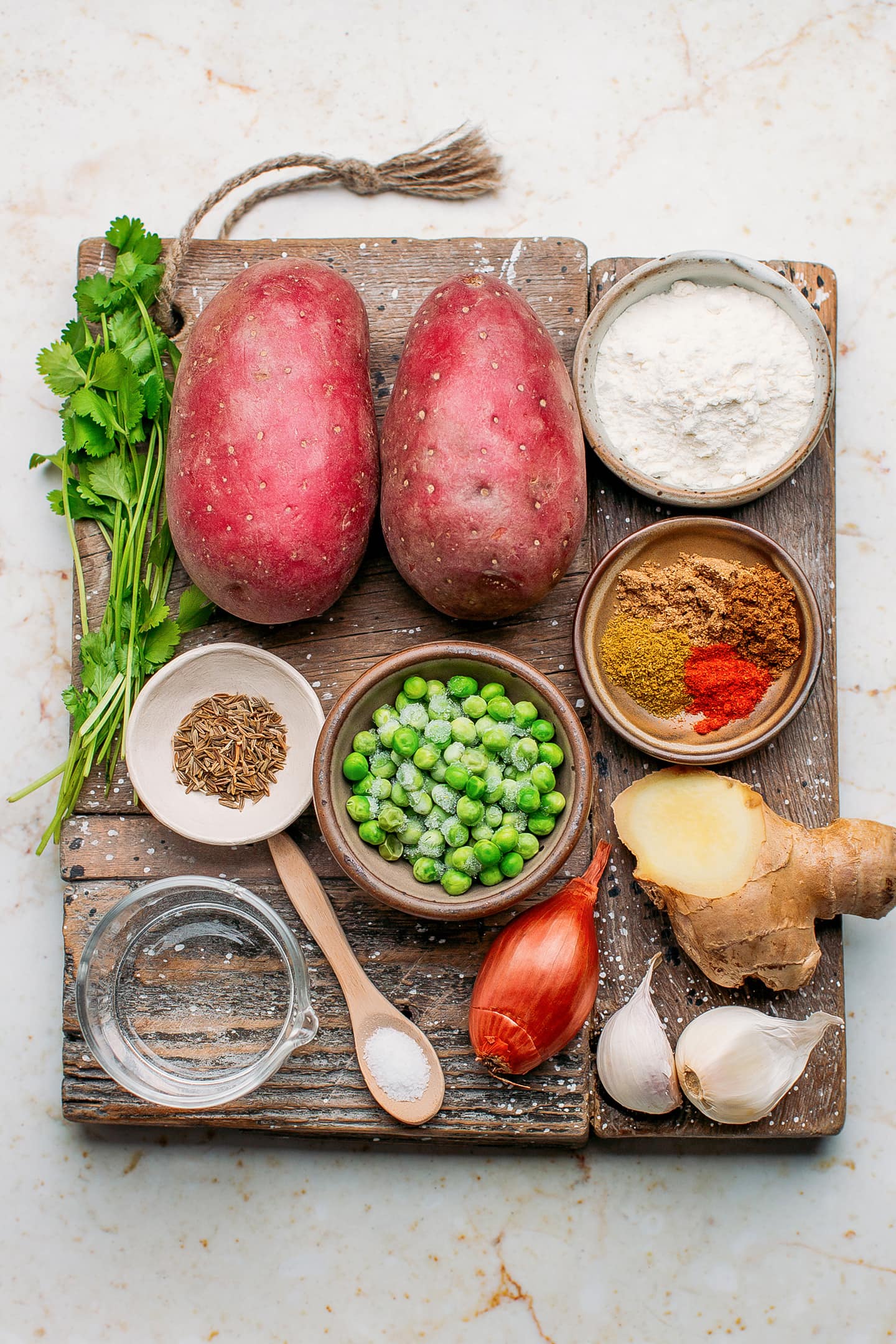 Ingredients like potatoes, green peas, shallots, garlic, and ginger.