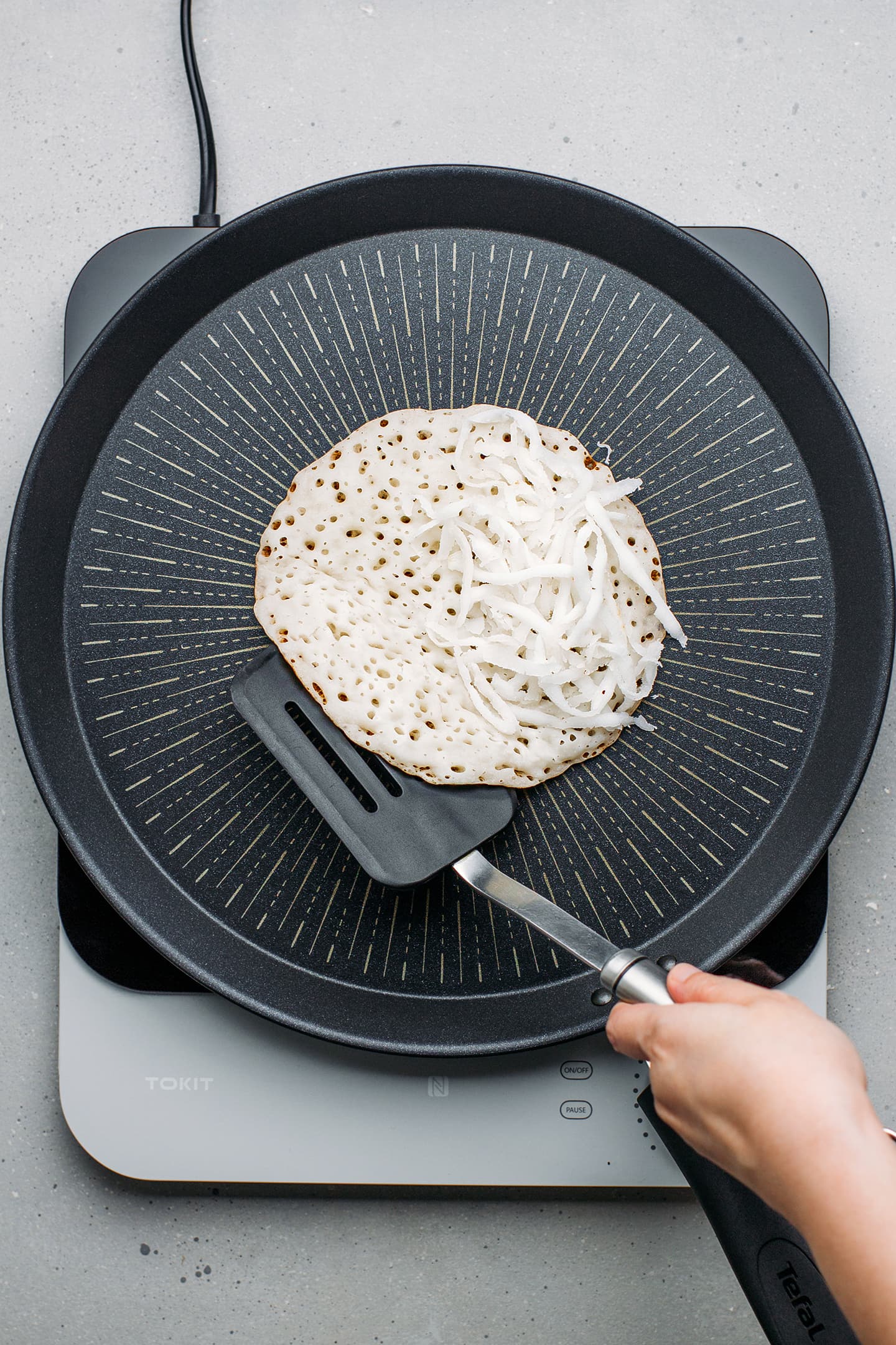 Folding coconut pancake on a non-stick skillet.